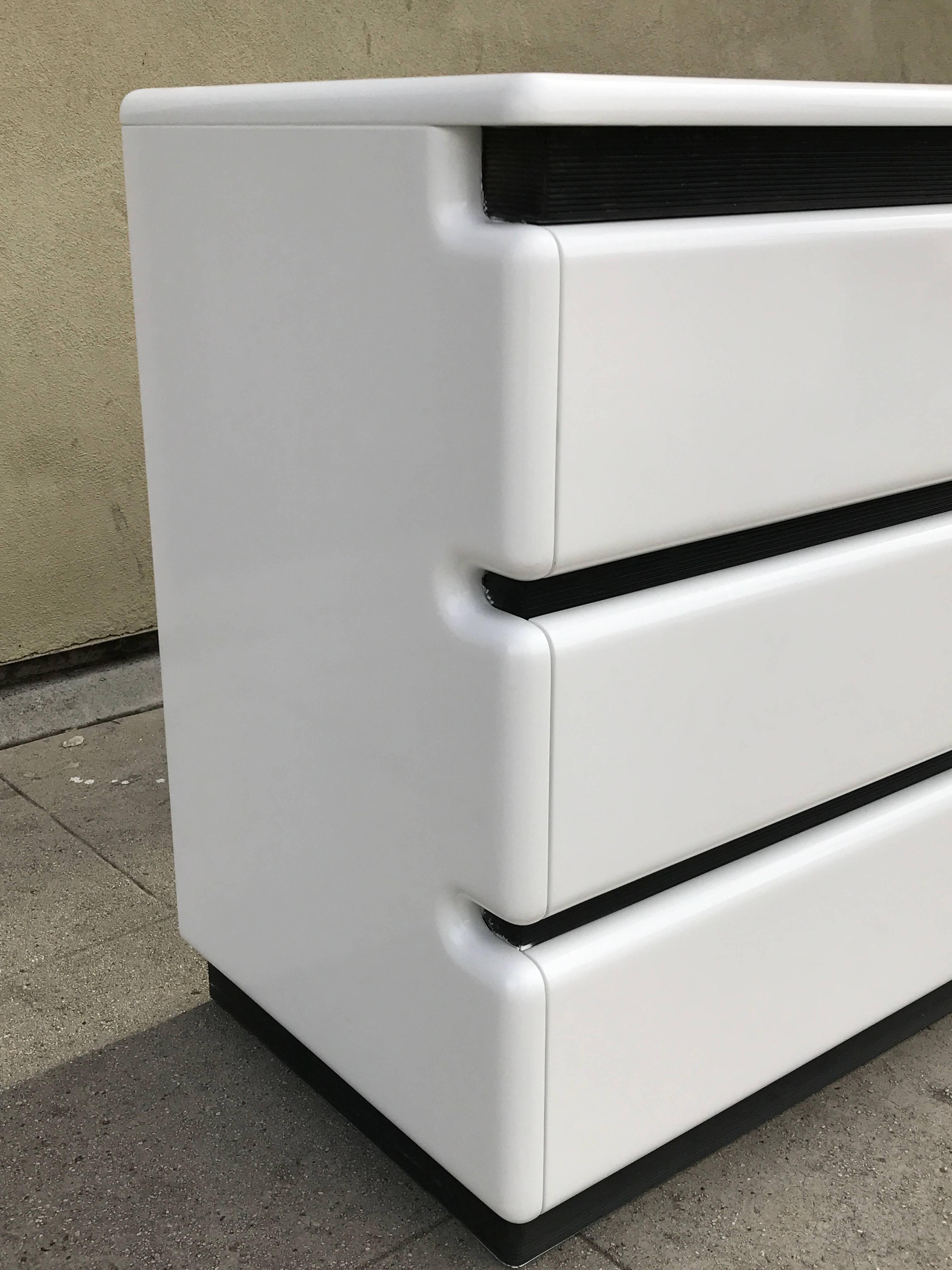 White lacquered minimalist dresser features six pull out drawers. Has a black corrugated detail between each drawer. Made in the 1970s by Maison Rougier.