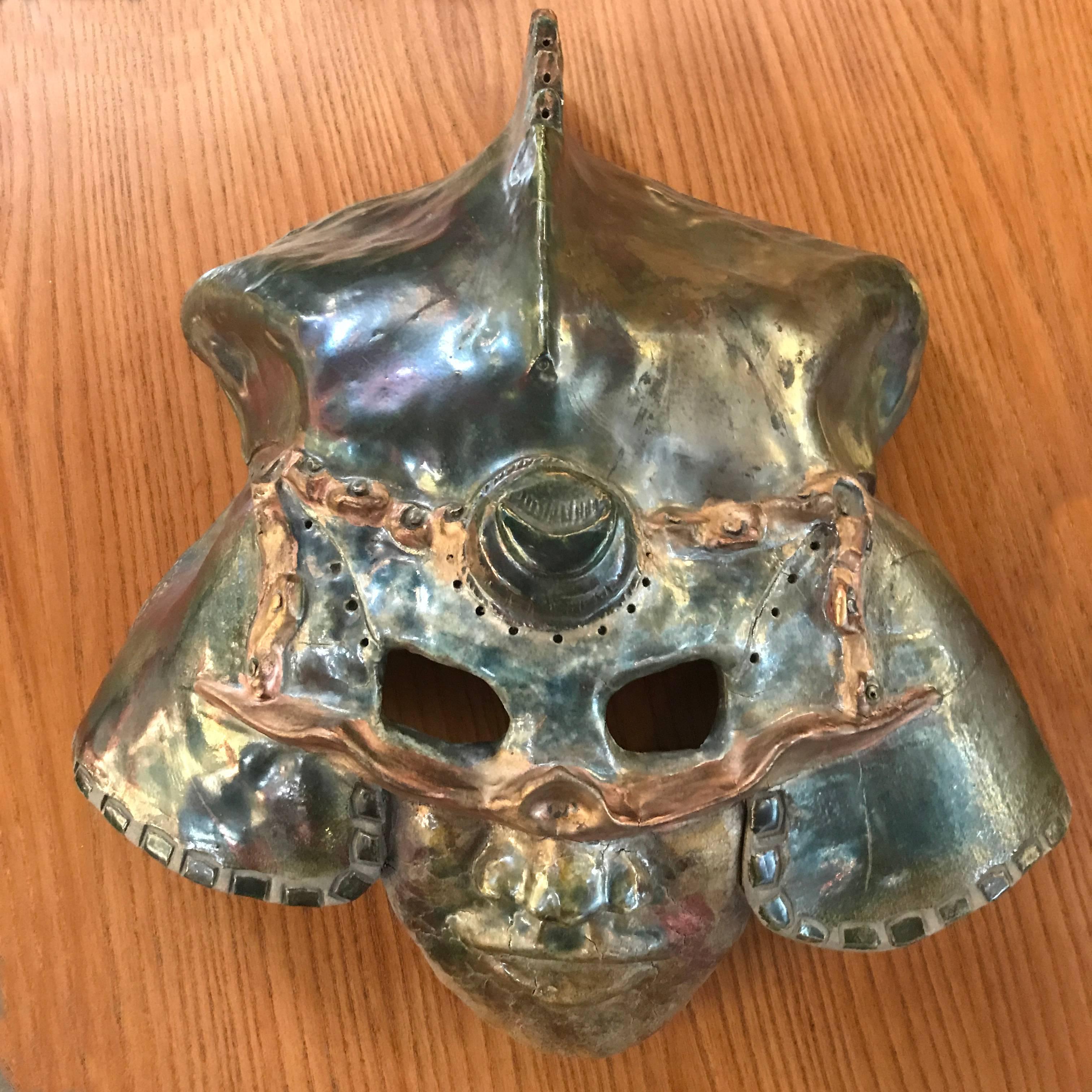 Raku style ceramic mask wall art of a warrior in a helmet.

Rakuware is Japanese hand-modelled pottery that is fired at a low temperature and rapidly cooled and typically used to make tea bowls. The technique became popular among American potters