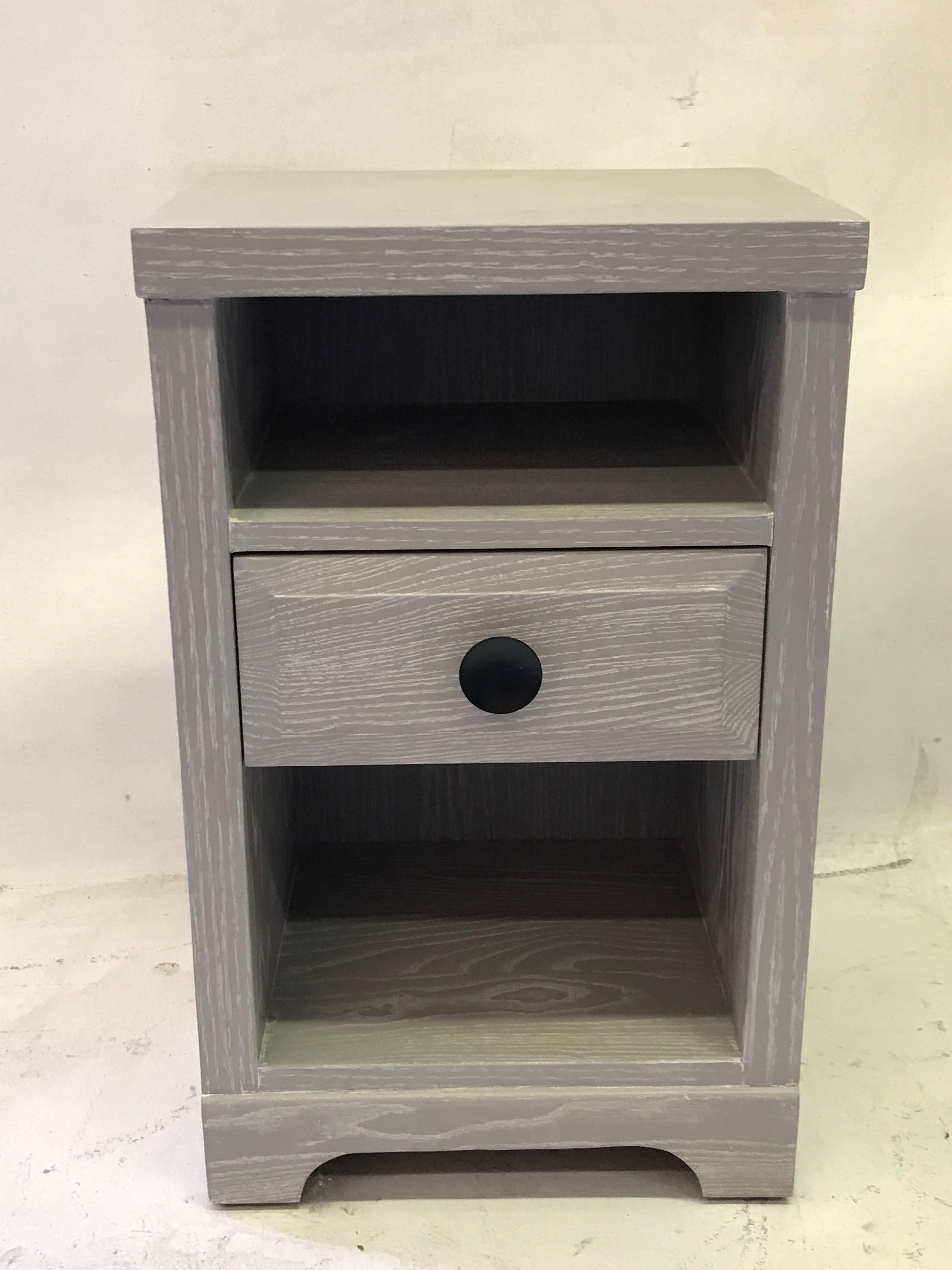 These nightstands are made of oak with a gray cerused finish.
They feature a drawer with a big black metal knob and two empty spaces.