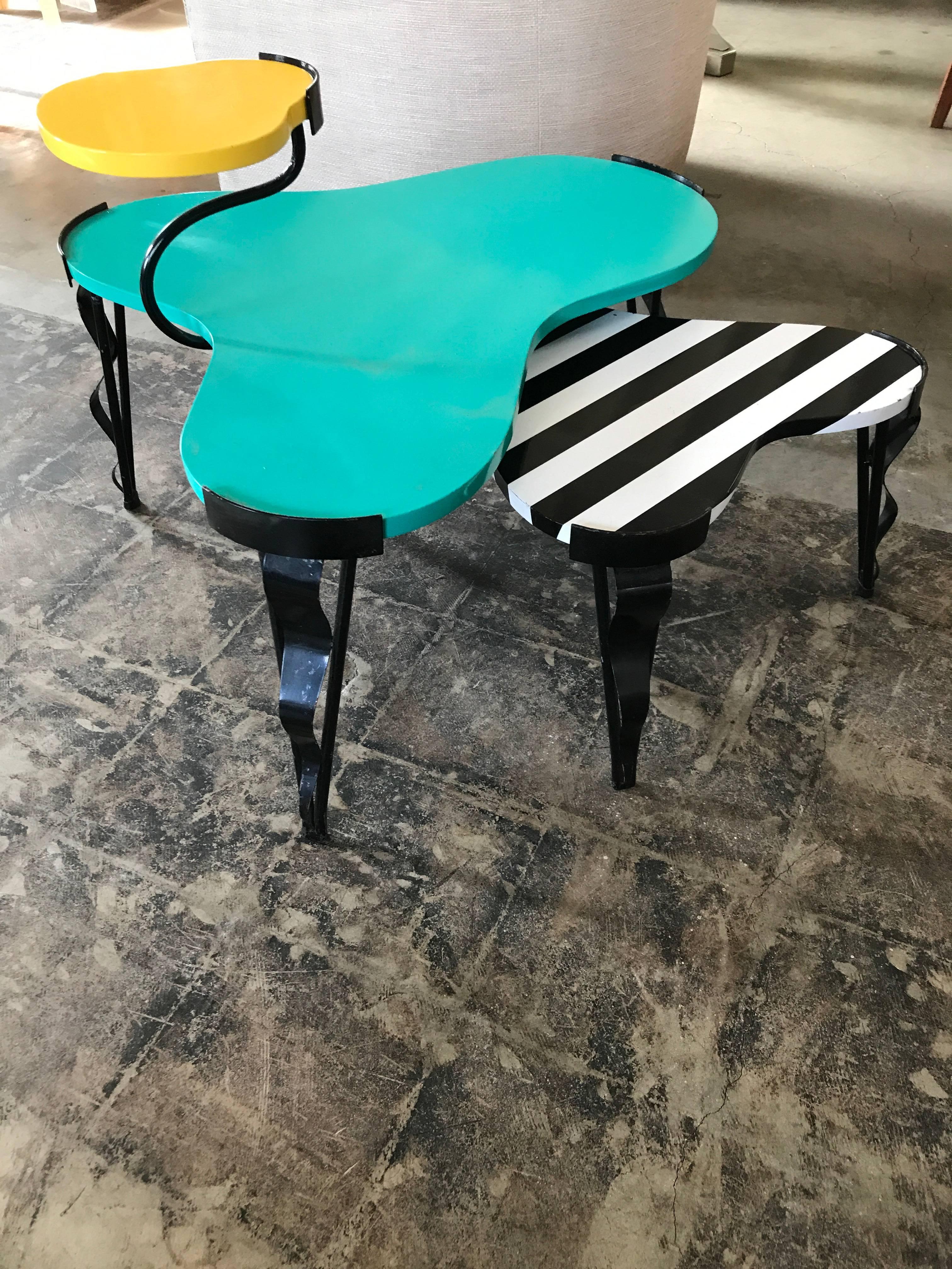 These Memphis inspired side tables are attributed to Los Angeles based designer Harry Siegel and built with a welded steel frame and a shaped, lacquered surface. The two-tiered top piece is finished in lemon yellow and teal lacquer with playful leg