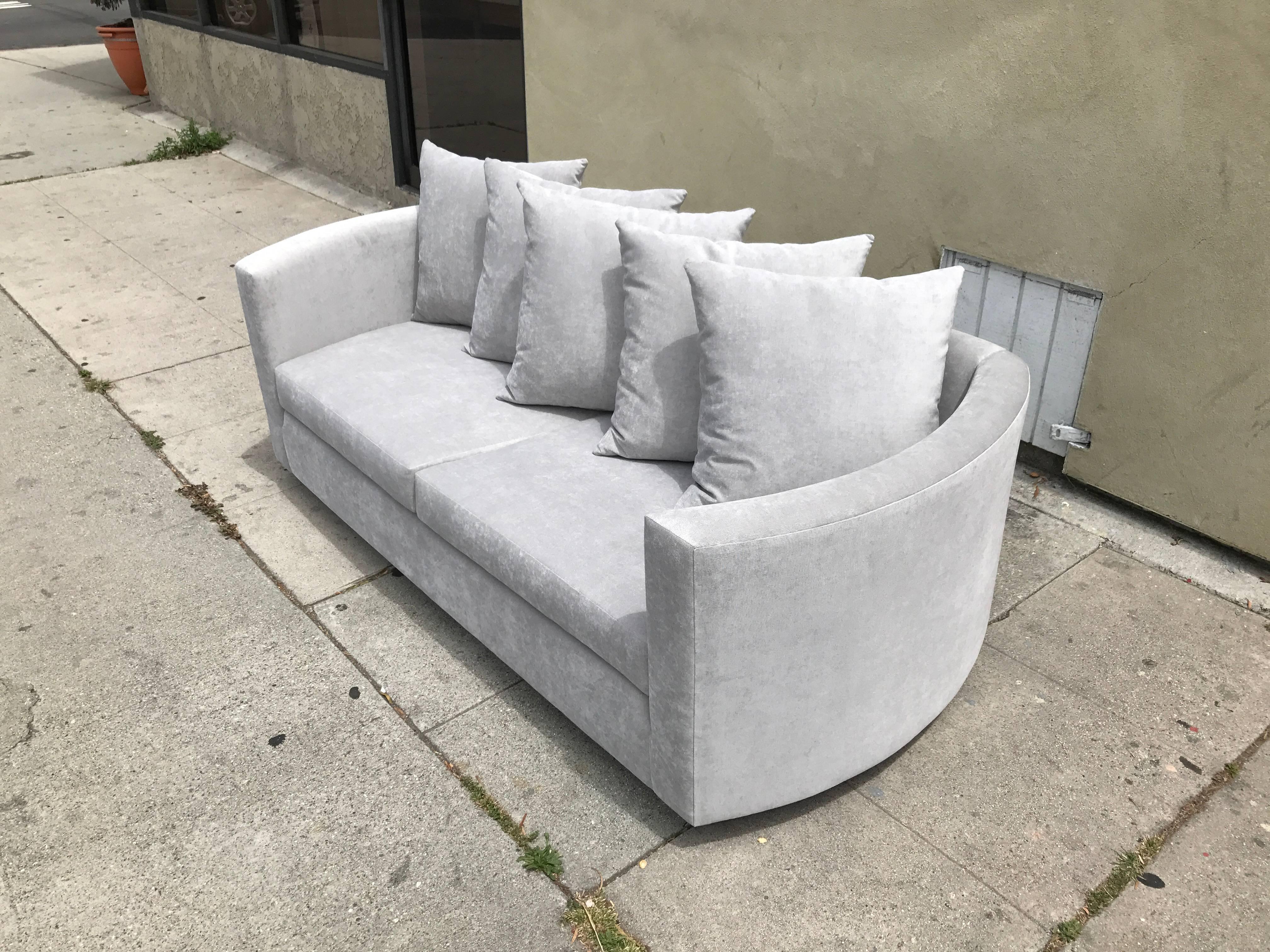 Newly reupholstered in dove gray fabric. Loveseat comes with five matching pillows.
It is curved on the arms and flat on the back which allows to set it against the wall.