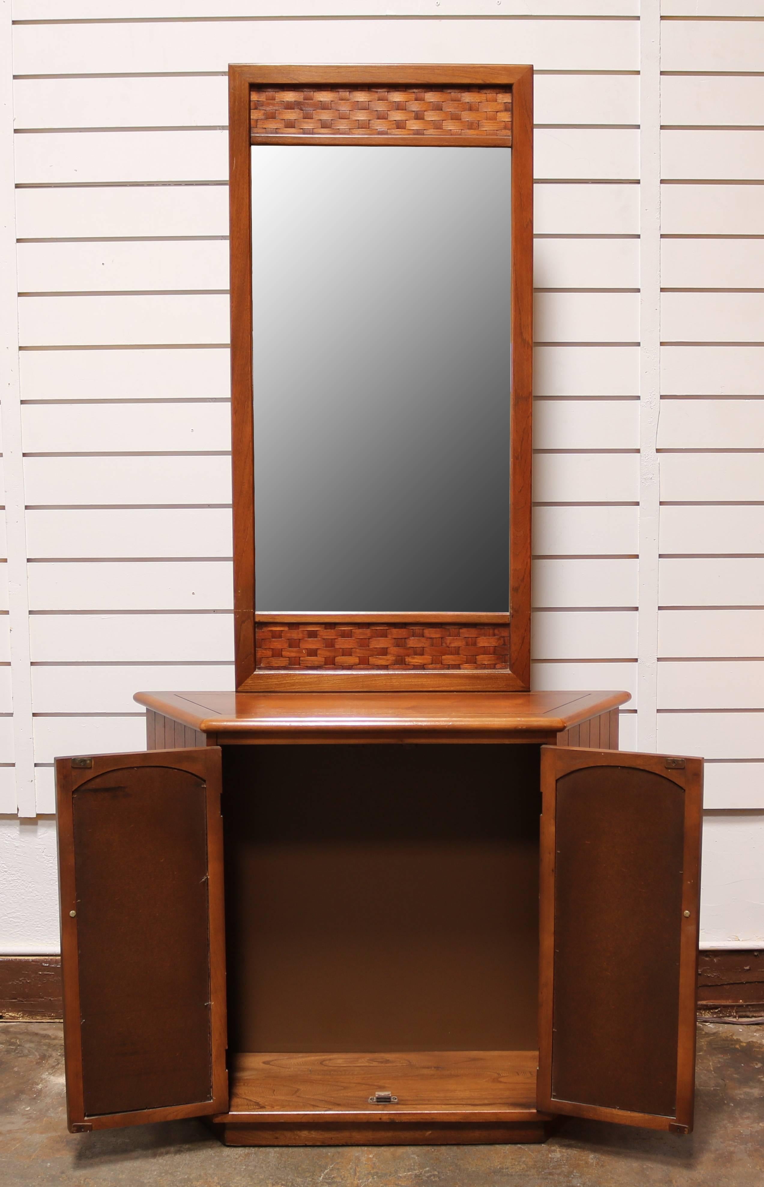 Entryway storage cabinet made of walnut, has a basket-weave detail on doors and around mirror. 



          