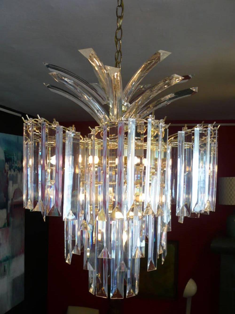 Glistening chandelier from the 1970s made of shaped Lucite crystals and a brass framework. The light source bounces the light from the central hub, reflecting throughout the Lucite.