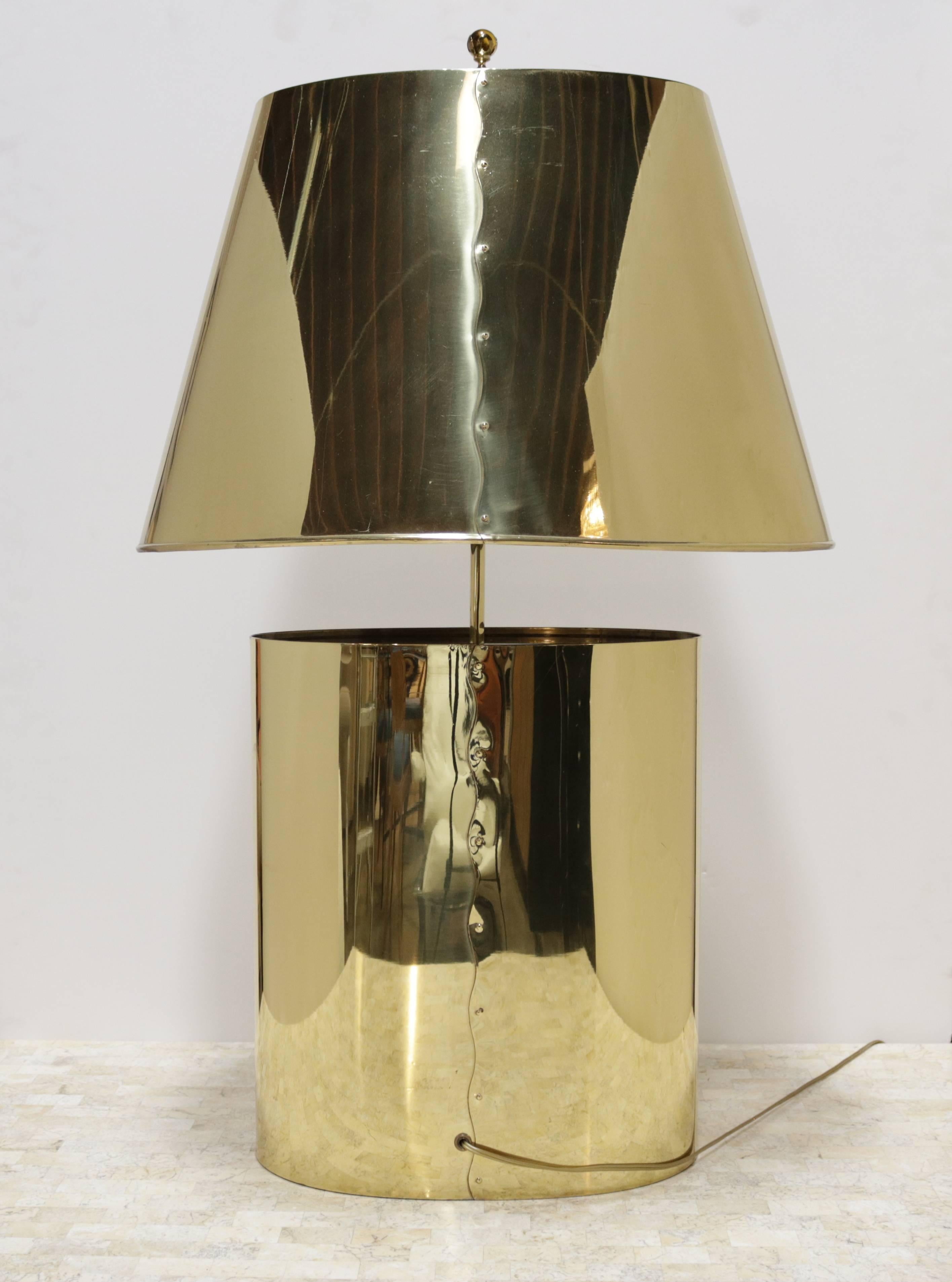 Golden polished brass table lamp from the 1970s. Both base and lampshade are constructed of gently folded brass and joined at one seam in a decorative manner. The finial is constructed of brass and glass. A bronze glass closes the base of the