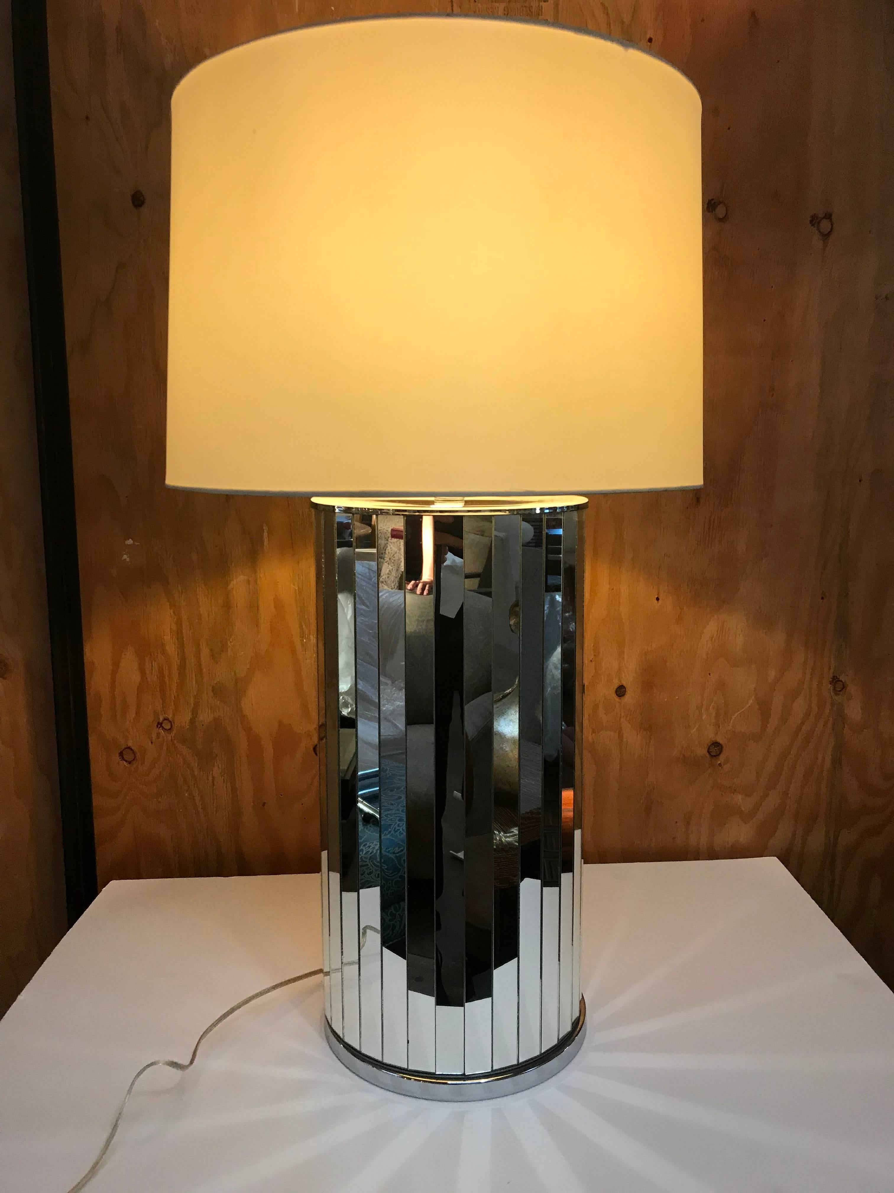 Glamorous 1970s table lamp with vertical mirrored panels around a column body with chromed top and bottom.
Wired and in working condition. Use 100W max bulbs. Original paper shade measures 12.5