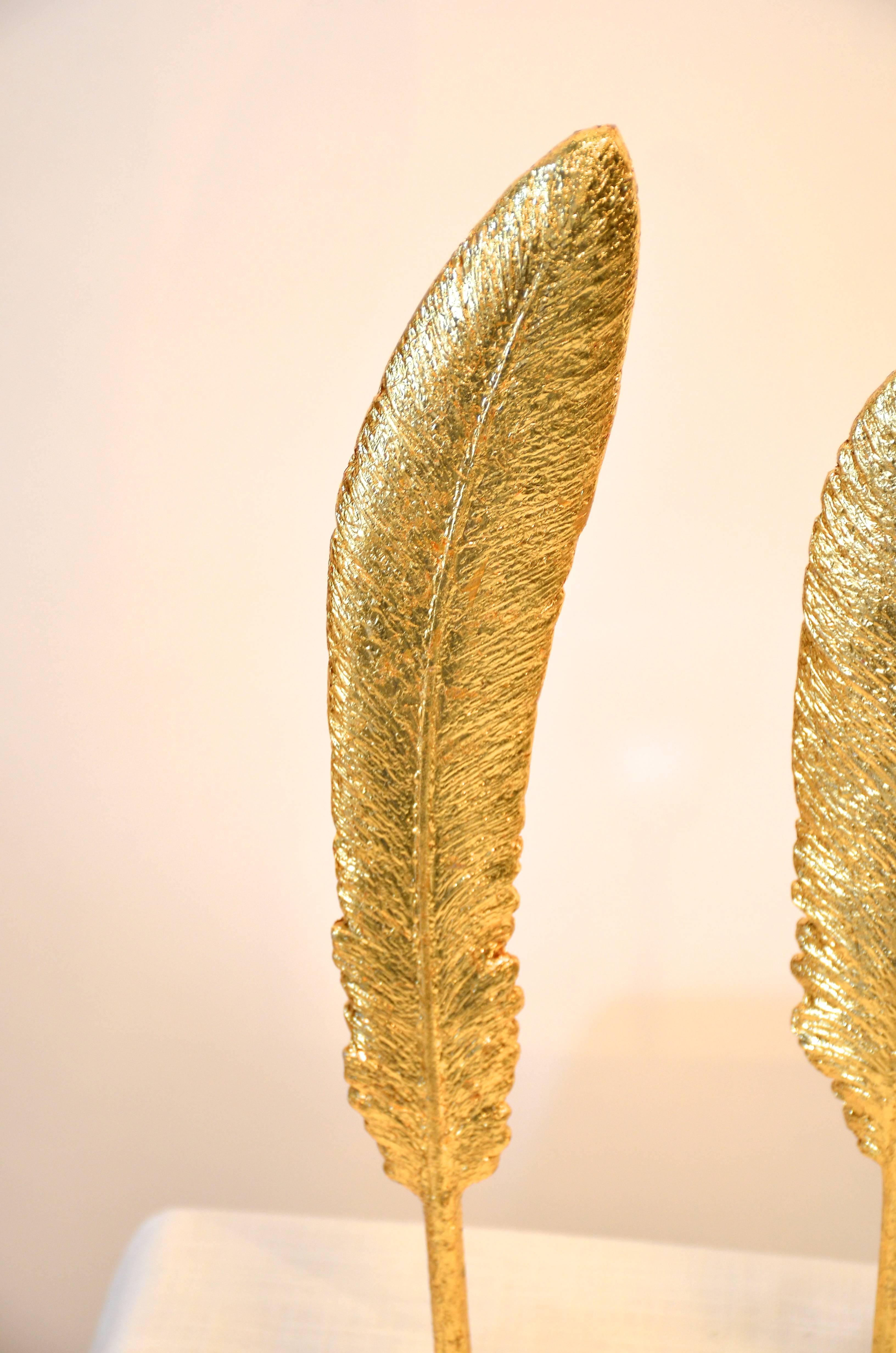 Trio of gold feathers mounted on Lucite blocks.