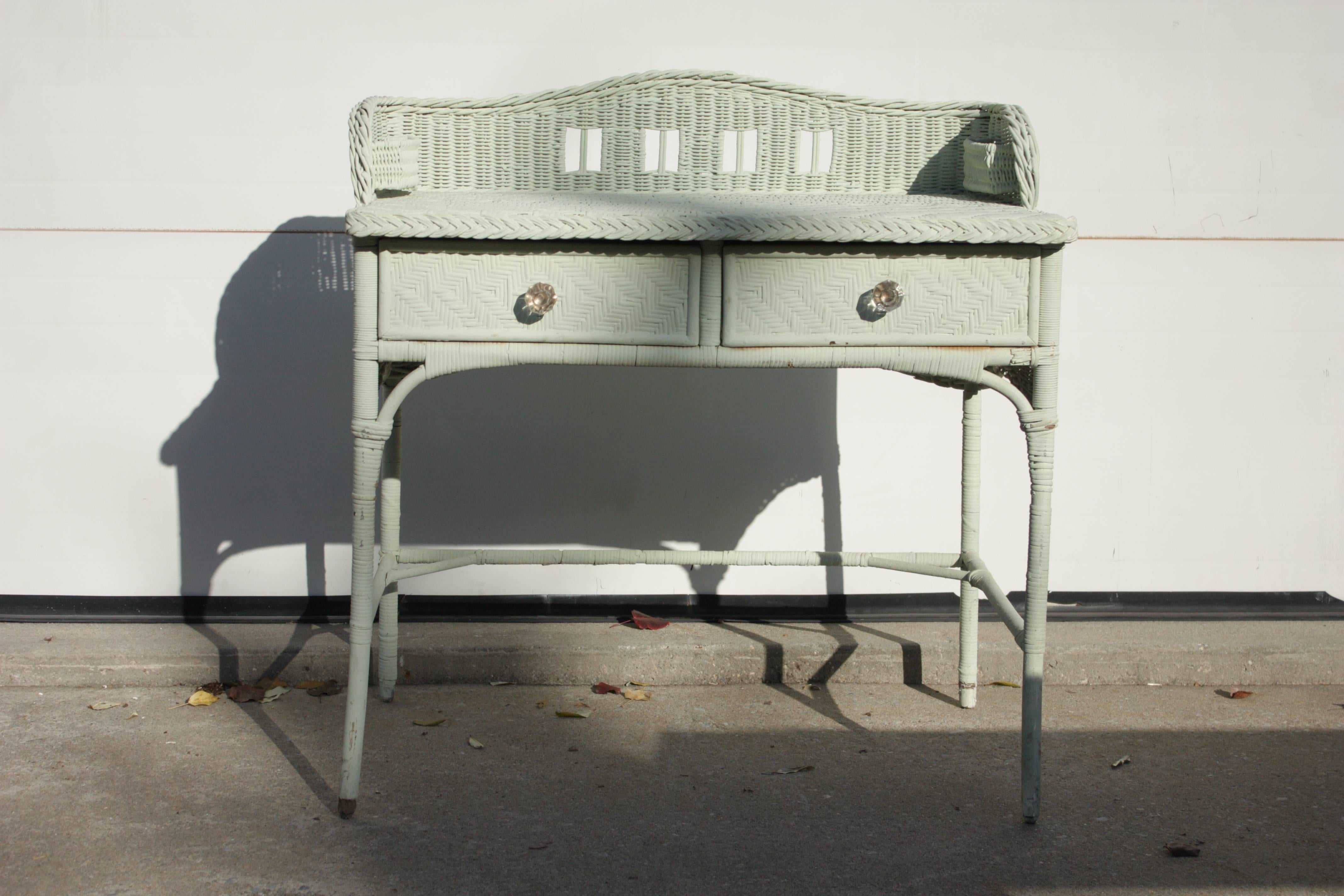 Vintage English Mint Seafoam Painted 1930s Writing Table Desk with two drawers, narrow legs and decorative cross support. Decorative clear pulls, cut-out camelback-style backsplash with functional and decorative single pocket fixed side baskets or