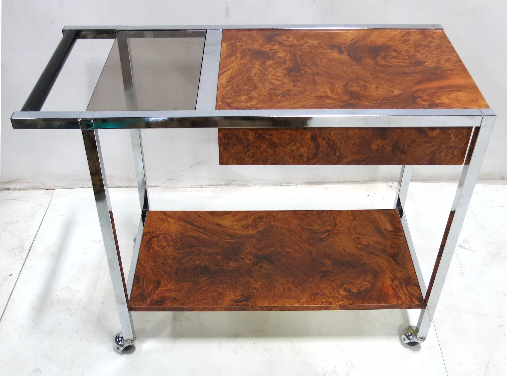 Handsome chrome and burl laminate bar trolley with chrome ball casters. Ebonized wood handle. The cart features a good sized drawer suspended from the underside of the chrome bordered top. Very nice quality materials and workmanship.