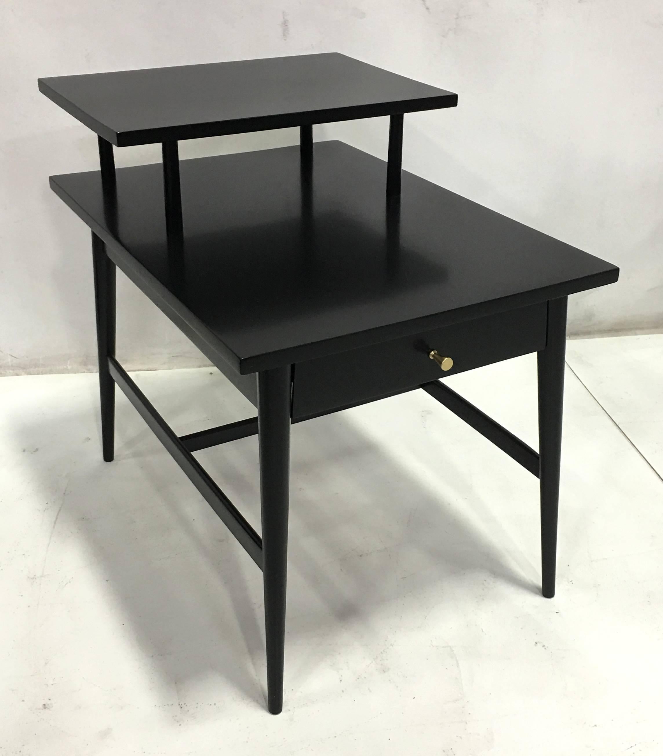 Handsome pair of Paul McCobb Planner Group nightstands or side tables painstakingly restored in black lacquer. The tables feature their original brass inverted cone pulls.  All work done with painstaking quality at our in-house workroom.  