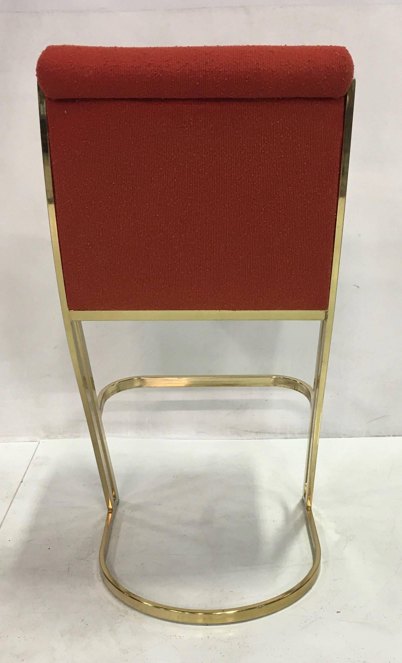 Set of three brass barstools upholstered in red wool twill in the style of Pierre Cardin.