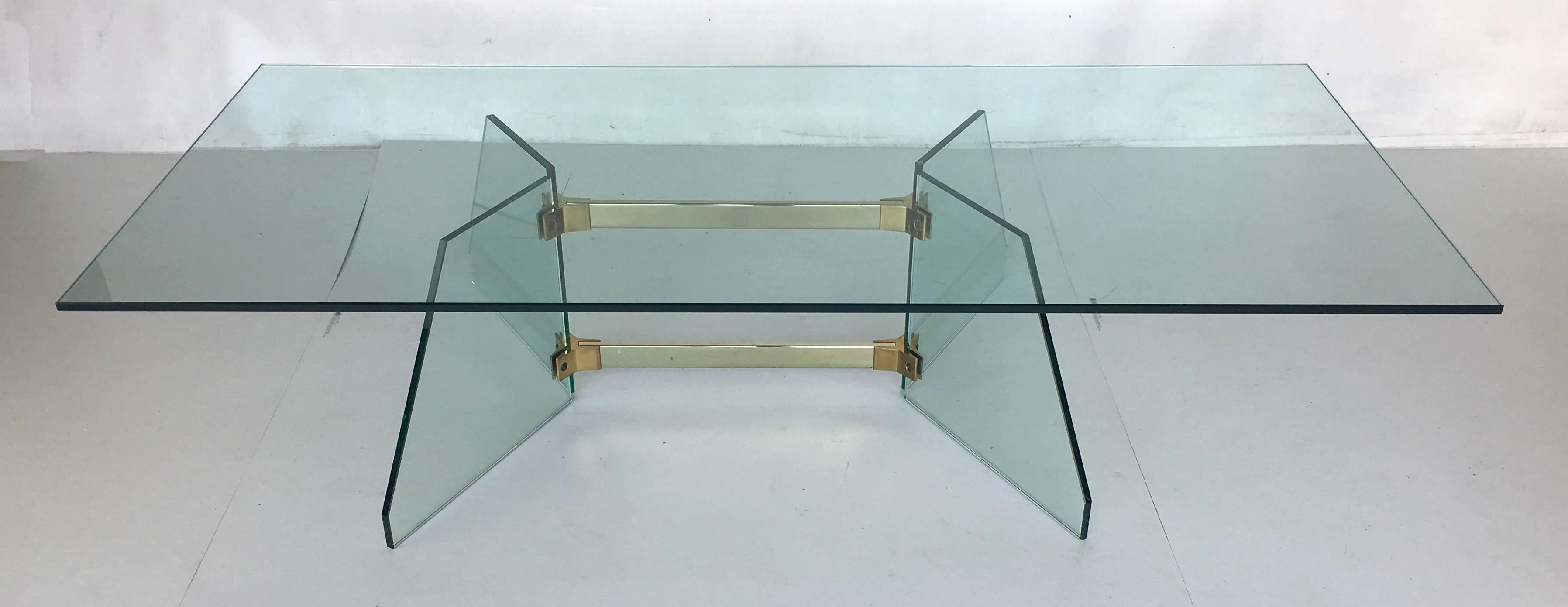Wonderful Modernist coffee table in the style of Fontana Arte. The table's eccentric base and brass stretchers support a large thick glass top.