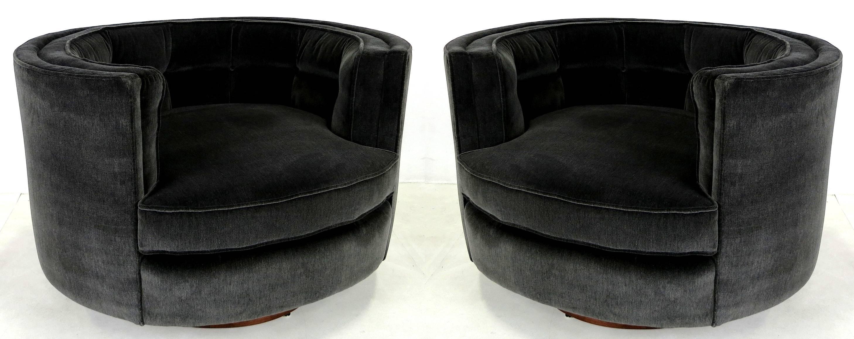 A handsome and super comfortable pair of oval lounge chairs with figured Walnut veneer swivel bases by Milo Baughman. The attached tufted back cushions make these chairs a versatile choice for TV watching, reading, or just lounging in supreme