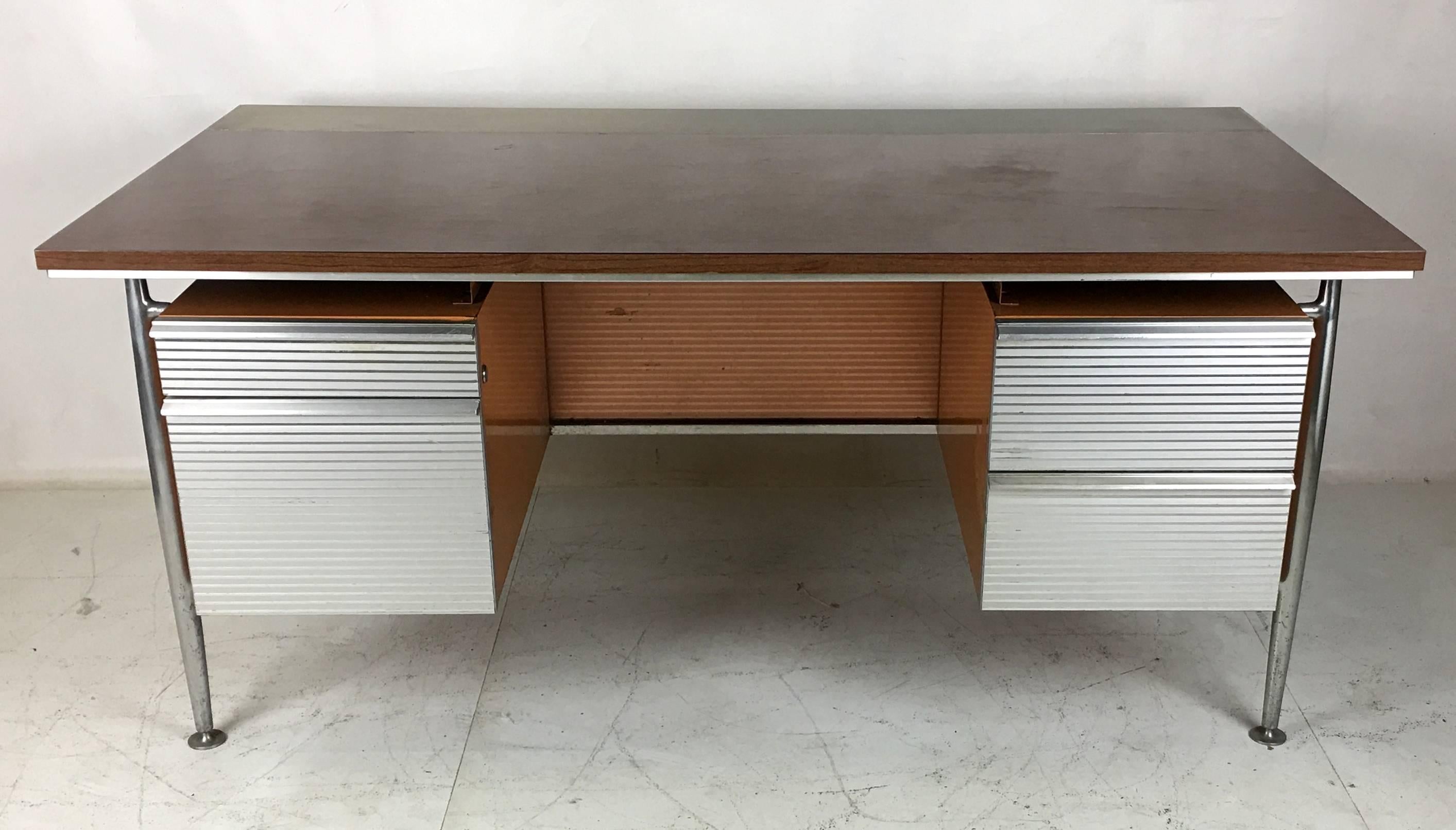 Aluminum and steel executive desk by the noted architect Welton Becket for his modernist icon that is the Kaiser Aluminum headquarters in Oakland, CA. The desk is in very good original condition. The top is wood-grain laminate with an aluminium