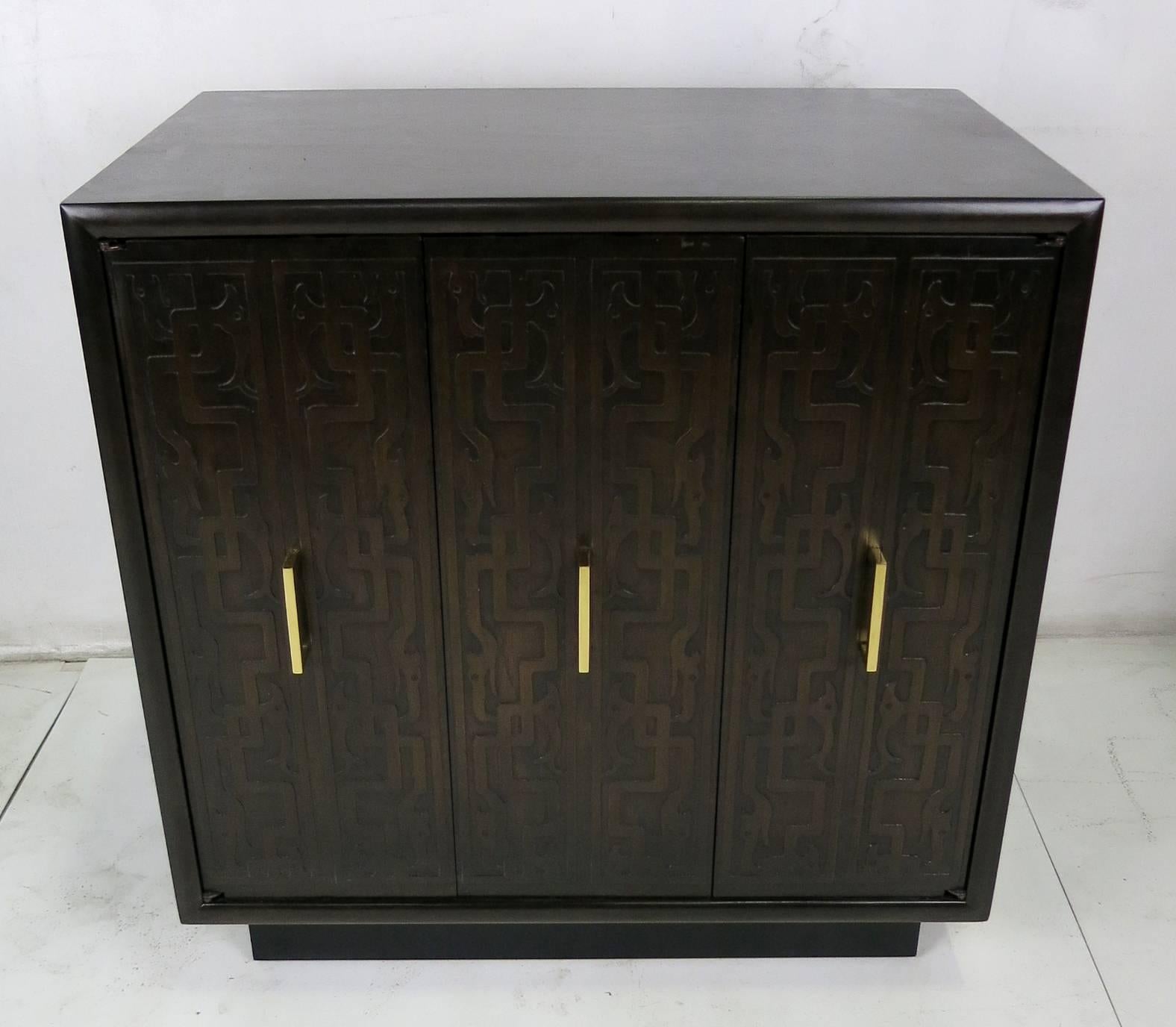 Fine pair of bedside cabinets with carved Tribal design doors. One pair of doors on each cabinet is a bi-fold type along with a single hinged door. Each door has a simple solid polished Brass handle. The cabinets are raised on ebonized wood plinth