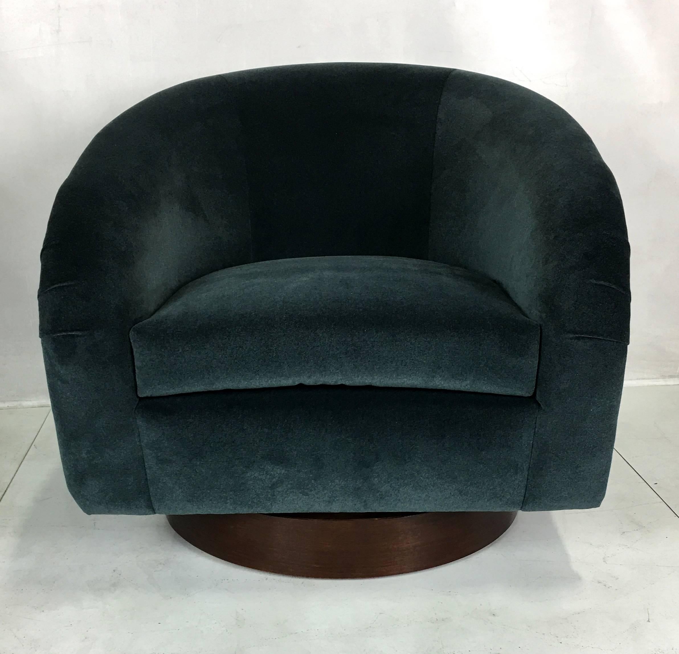 Pair of swivel lounge chairs by Milo Baughman. The pair have been restored from the ground up; reglued, reupholstered, refinished bases, new swivel plates, foam and Dacron, and covered in a luxurious heavyweight charcoal grey velvet.
