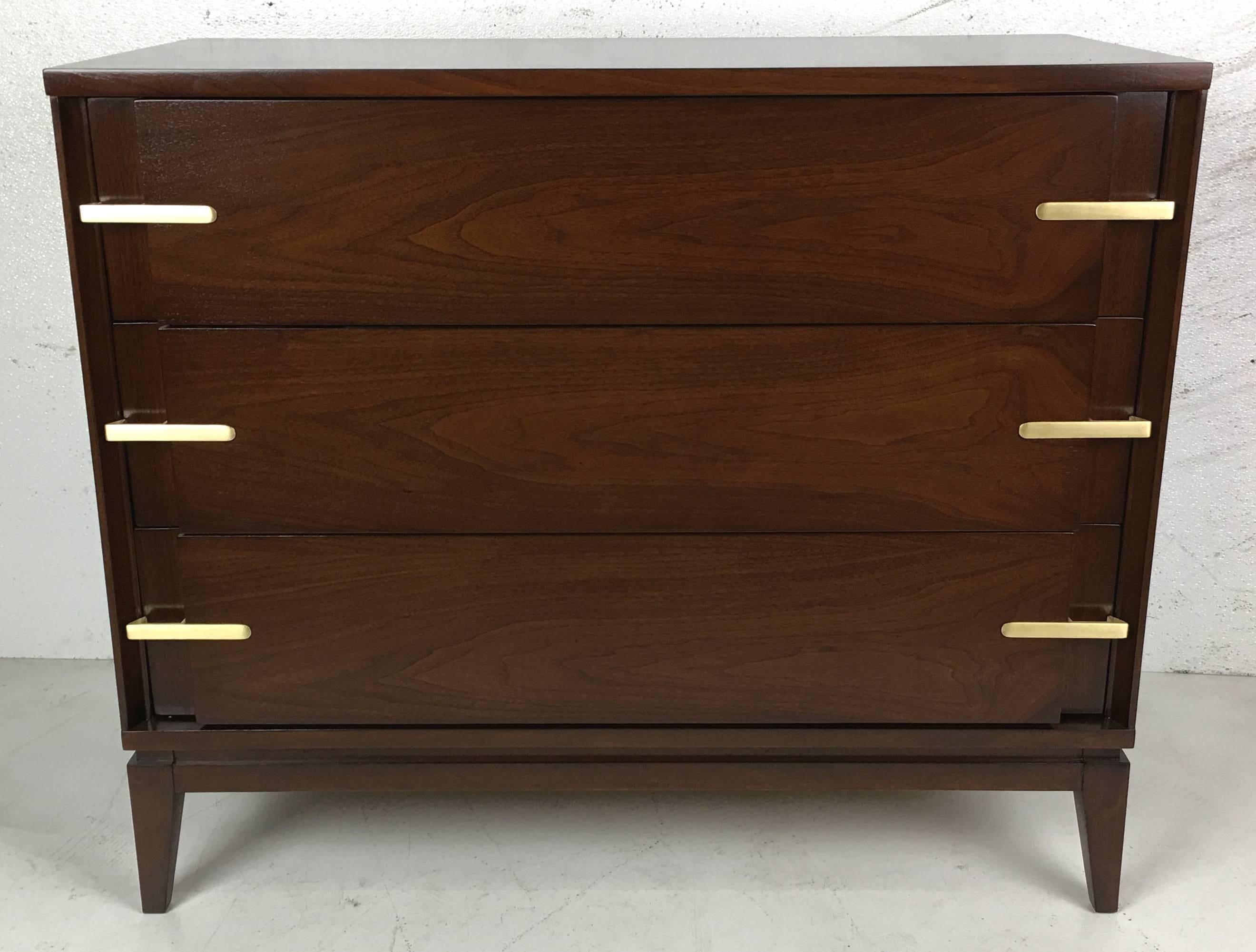 Beautifully grained pair of walnut bachelors chests with inset brass pulls. The pair have been meticulously restored in medium brown lacquer. The drawer pulls have been refinished to a light brushed finish. The chests are reminiscent
of designs by