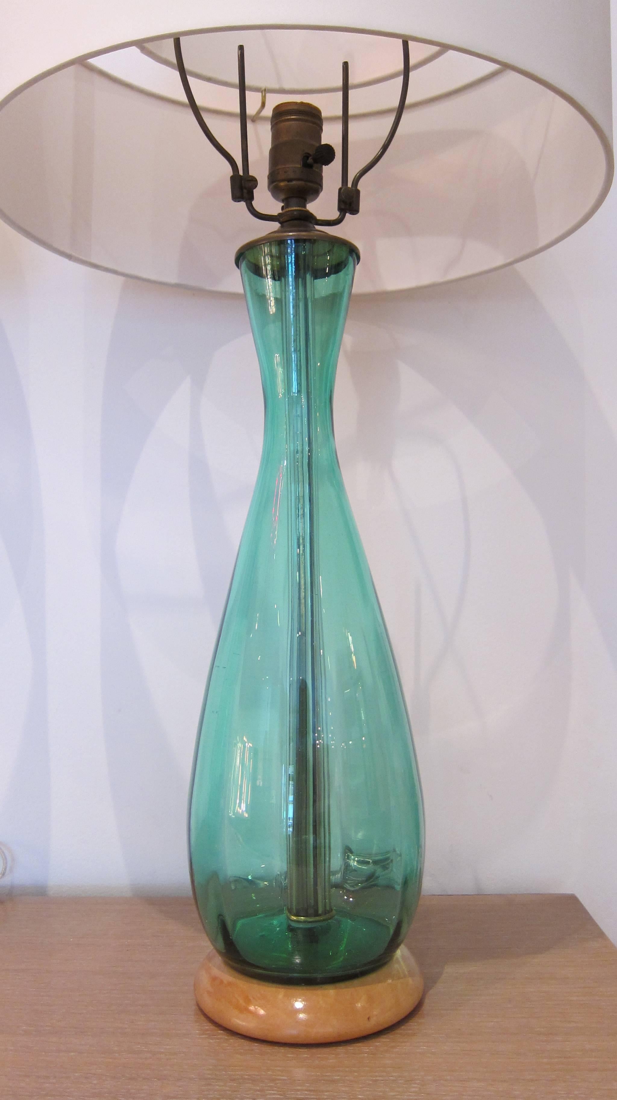 Pair of blue green glass table lamps with matching finials, each of baluster form, raised on a circular wooden base. Height overall 33 inches. Comes with custom made shades.