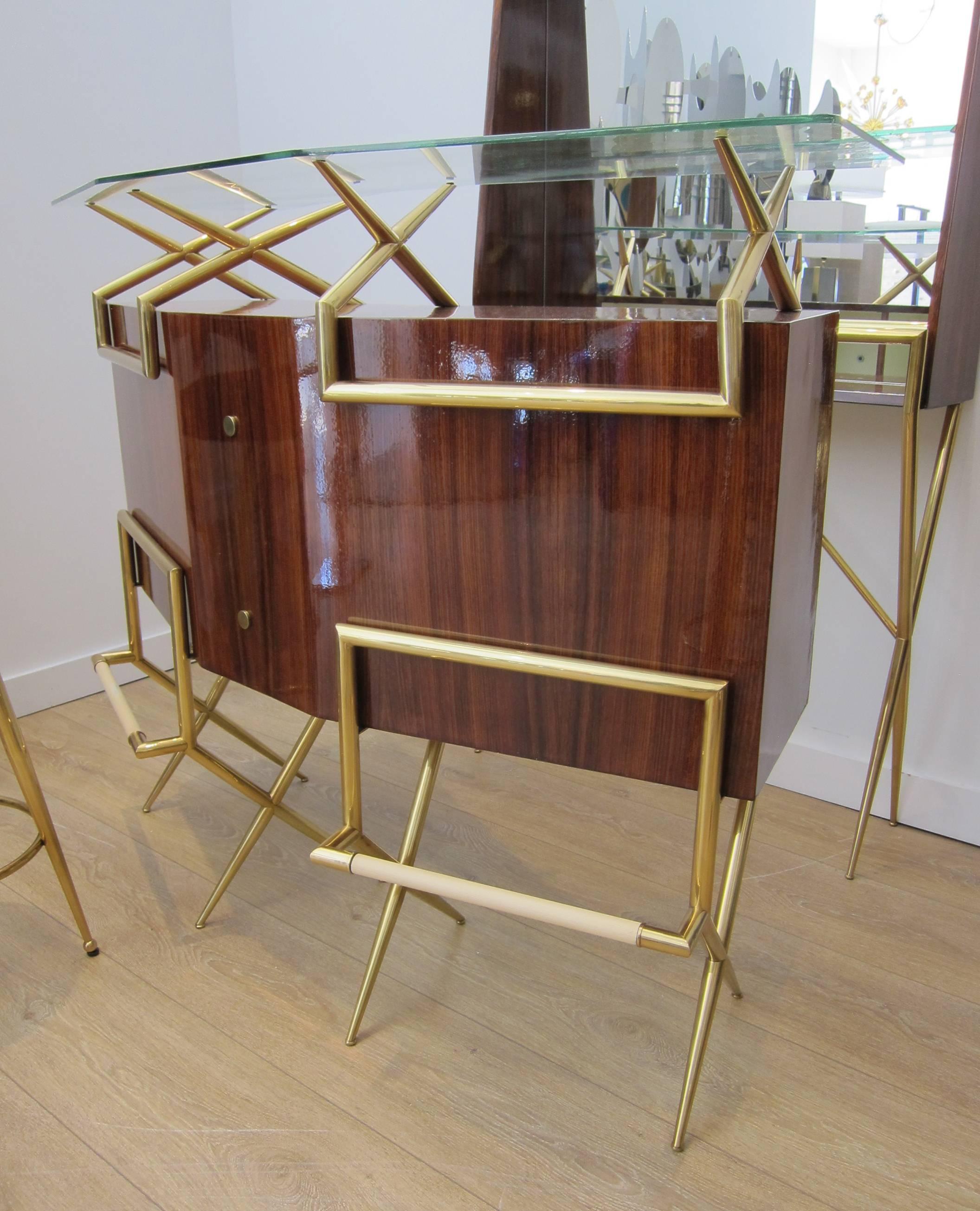 An exceptional Mid-Century Modern rosewood and brass Italian bar suite comprised of a dry bar, two brass bar stools and bar back/vitrine.
Wood work and brass restored to perfection. Newly upholstered with faux black hide.
