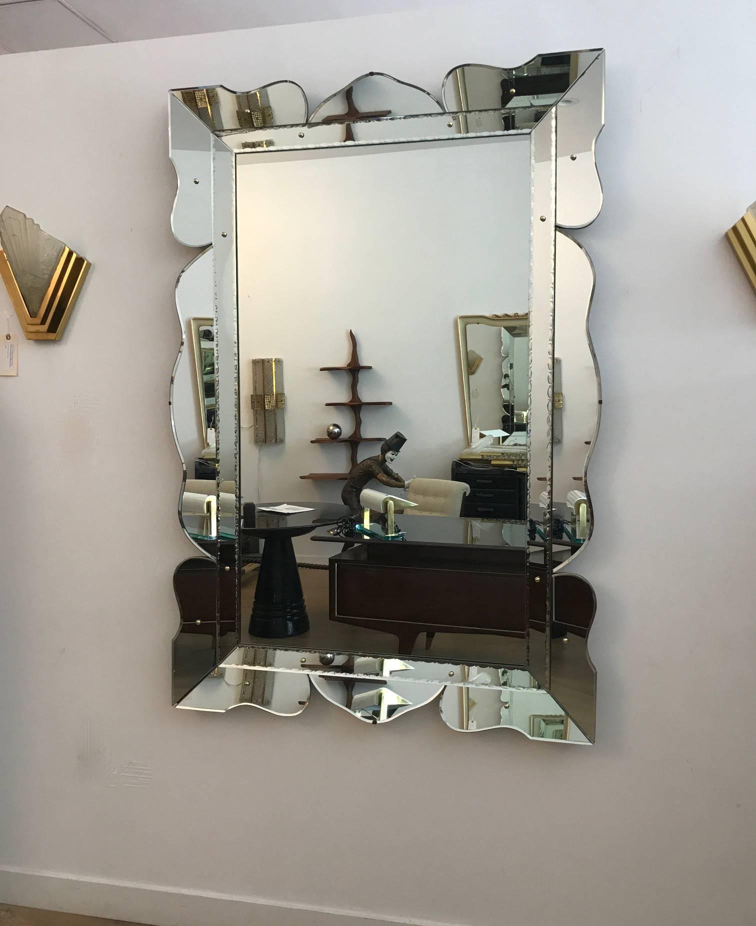 monumental vintage Hollywood regency style scalloped mirror circa 1950.The frame consists of scalloped beveled mirror panels with brass cap accents. We are showing this mirror in a portrait format but can be hung horizontally. 


