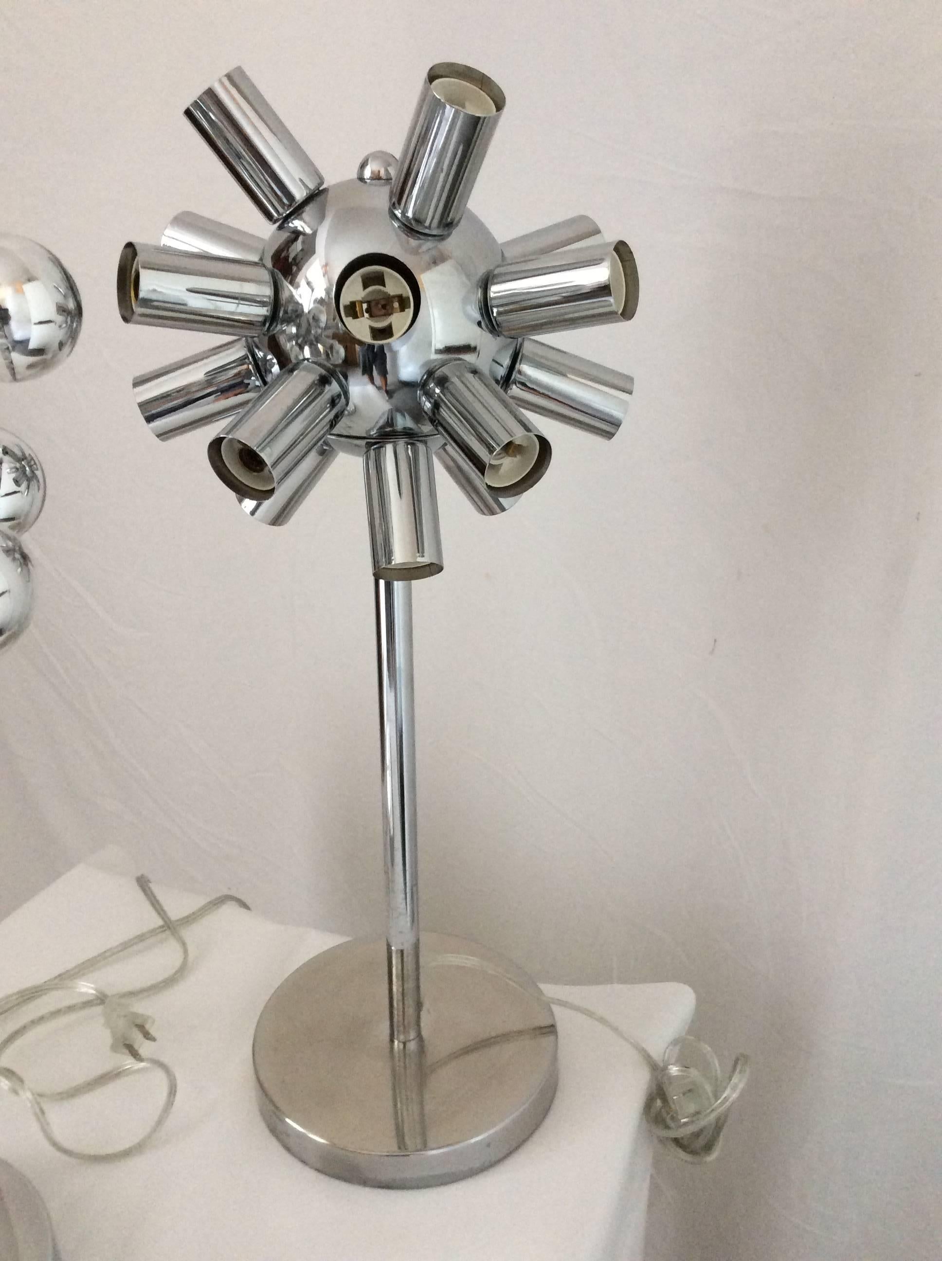 You are looking at a pair of table lamps in the Sputnik style. They are made of metal with chrome fin. Each lamp has a round base and a center stem which has a round globe from which 16 bulbs are arranged around it. Lamps have that cool retro feel.