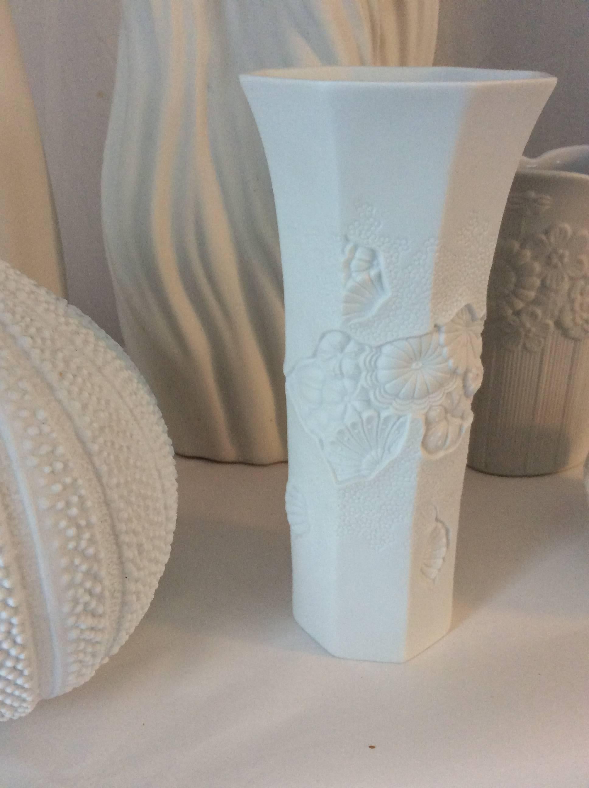 You are looking at a collection of six white bisque porcelain vases and one bowl with lid. They are all different size and shapes which makes for a nice vignette. Only one of the pieces is signed - Kaiser, octagonal shape in foreground and the