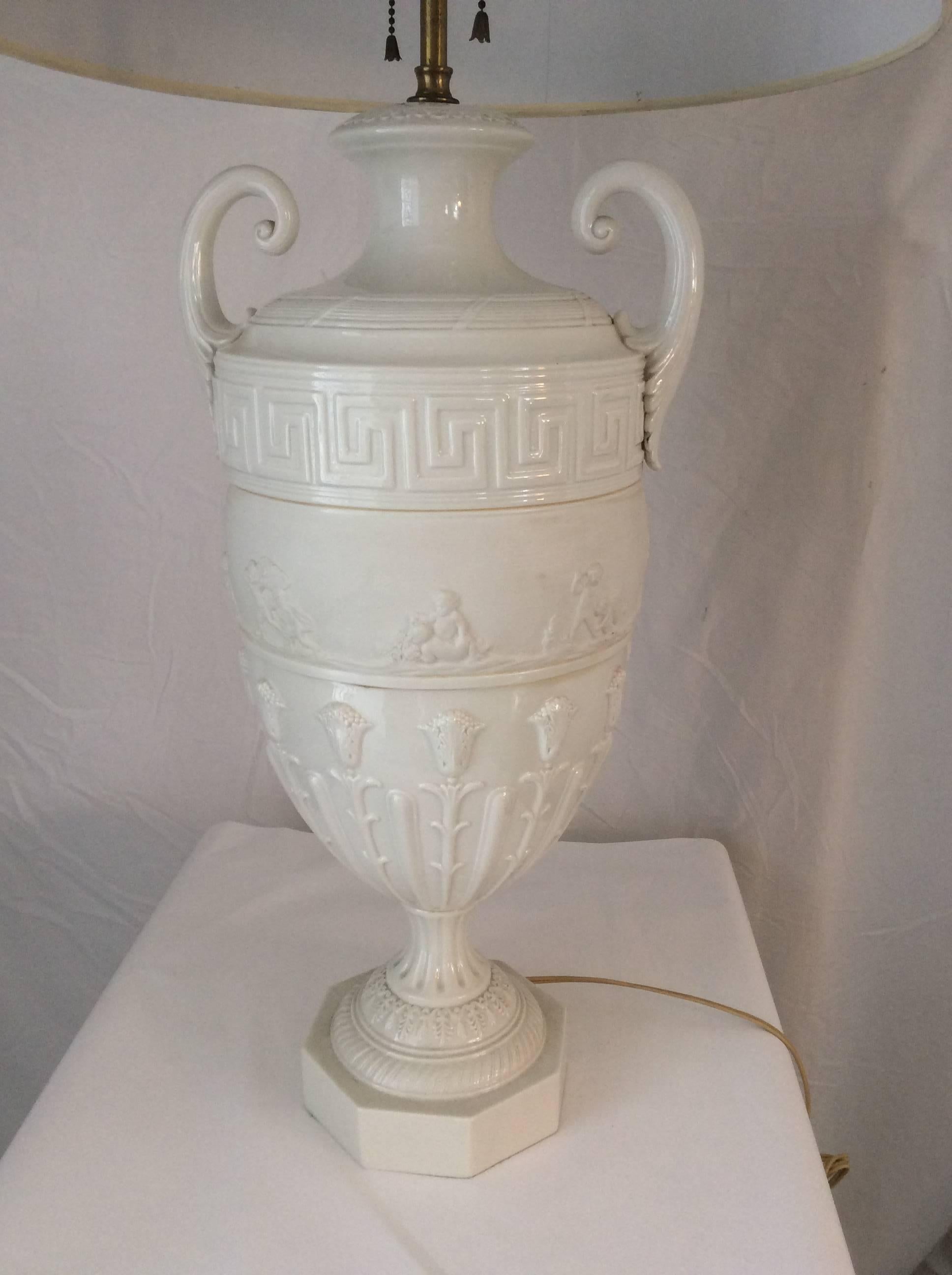 You are looking at a stunning Italian table lamp. Made in the classical style, this urn shape lamp with Greek key motif and raised foliage pattern is very elegant. It has a banding of small raised puttis frolicking in a matte white bisque finish to