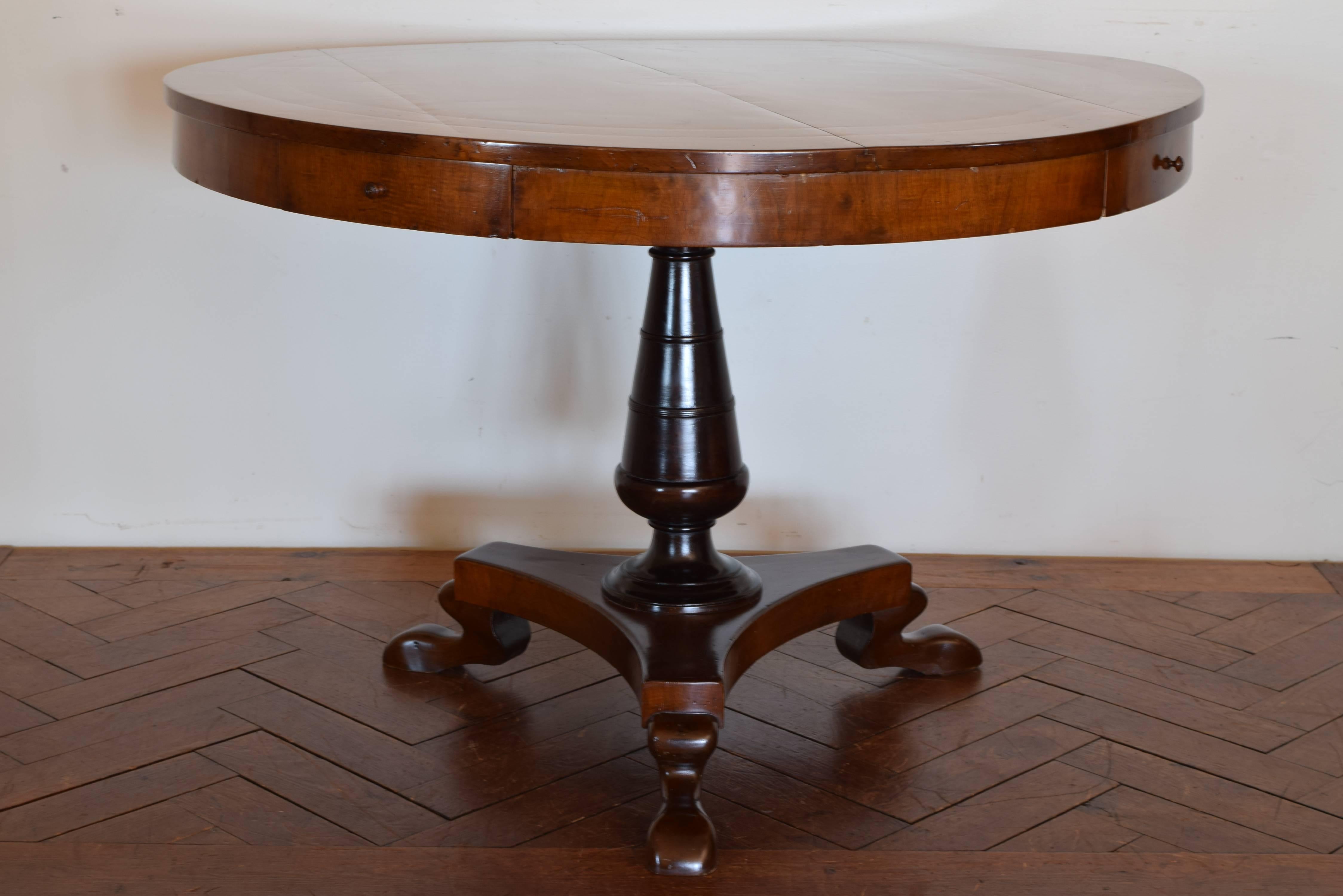 Italian late neoclassic walnut and ebonized four-drawer center table, circa 1830-1840. The round top having band inlays and a centered inlaid star medallion and housing four drawers, the tapering standard is ebonized and resting atop a tripartite
