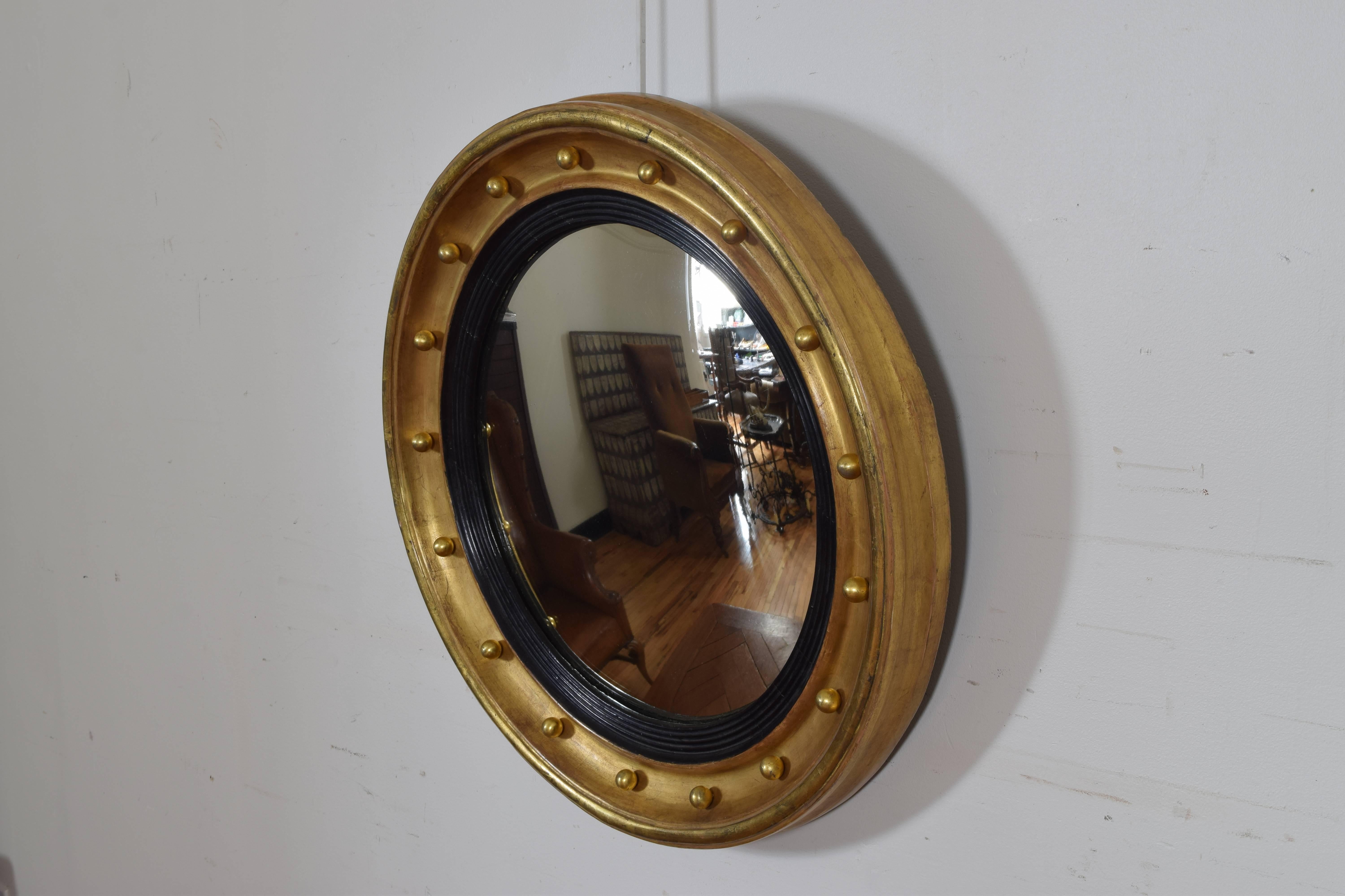 The round frame with molded edges and having gilded spheres along the interior convex scoop, the inner edge of ebonized molded wood, retaining original convex mirrorplate.
