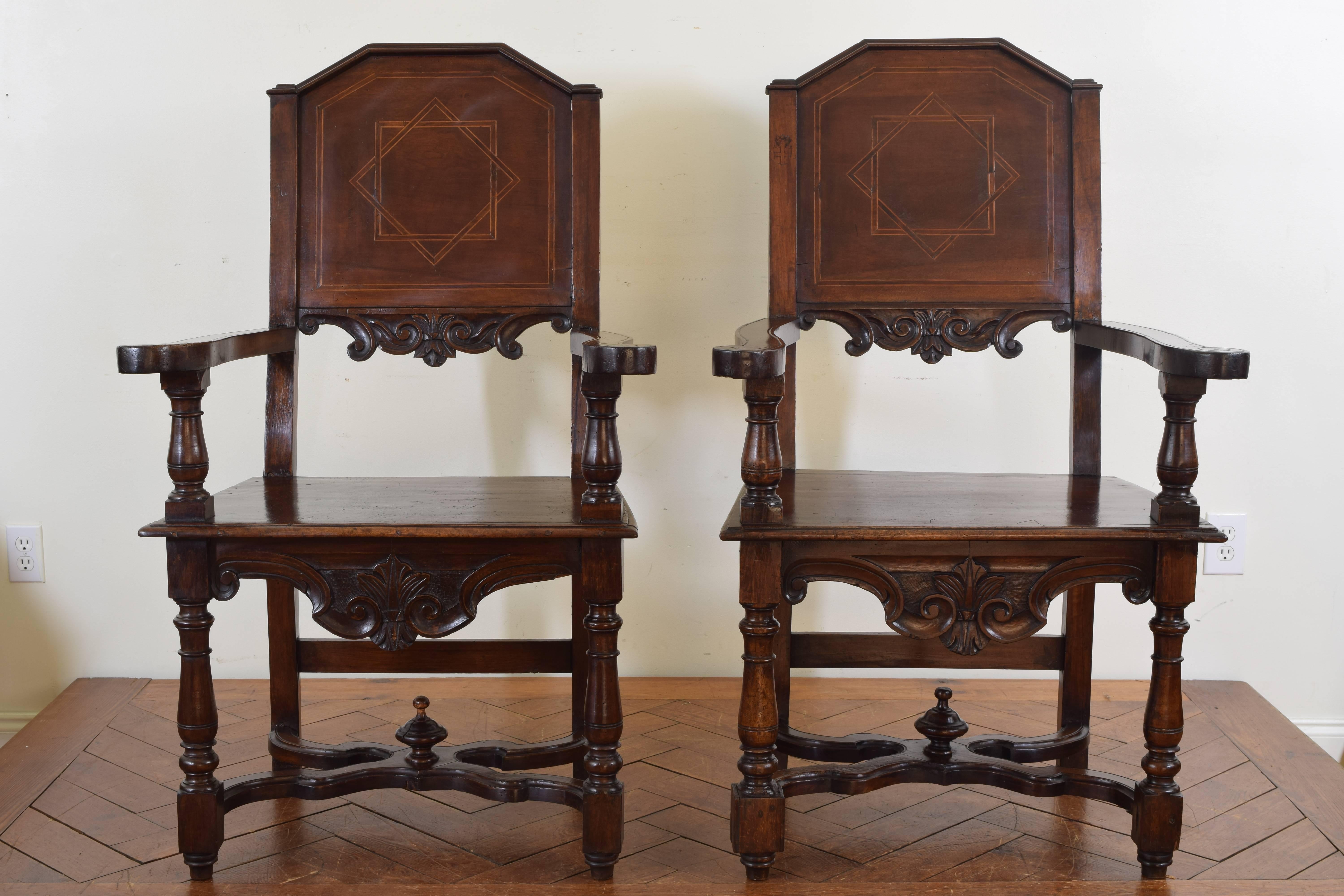 The backrests with a slight lean and having shaped arches, the lower section of the backrests carved, generous seats and curving arms supported by turned legs joined by X-form stretchers with finials.