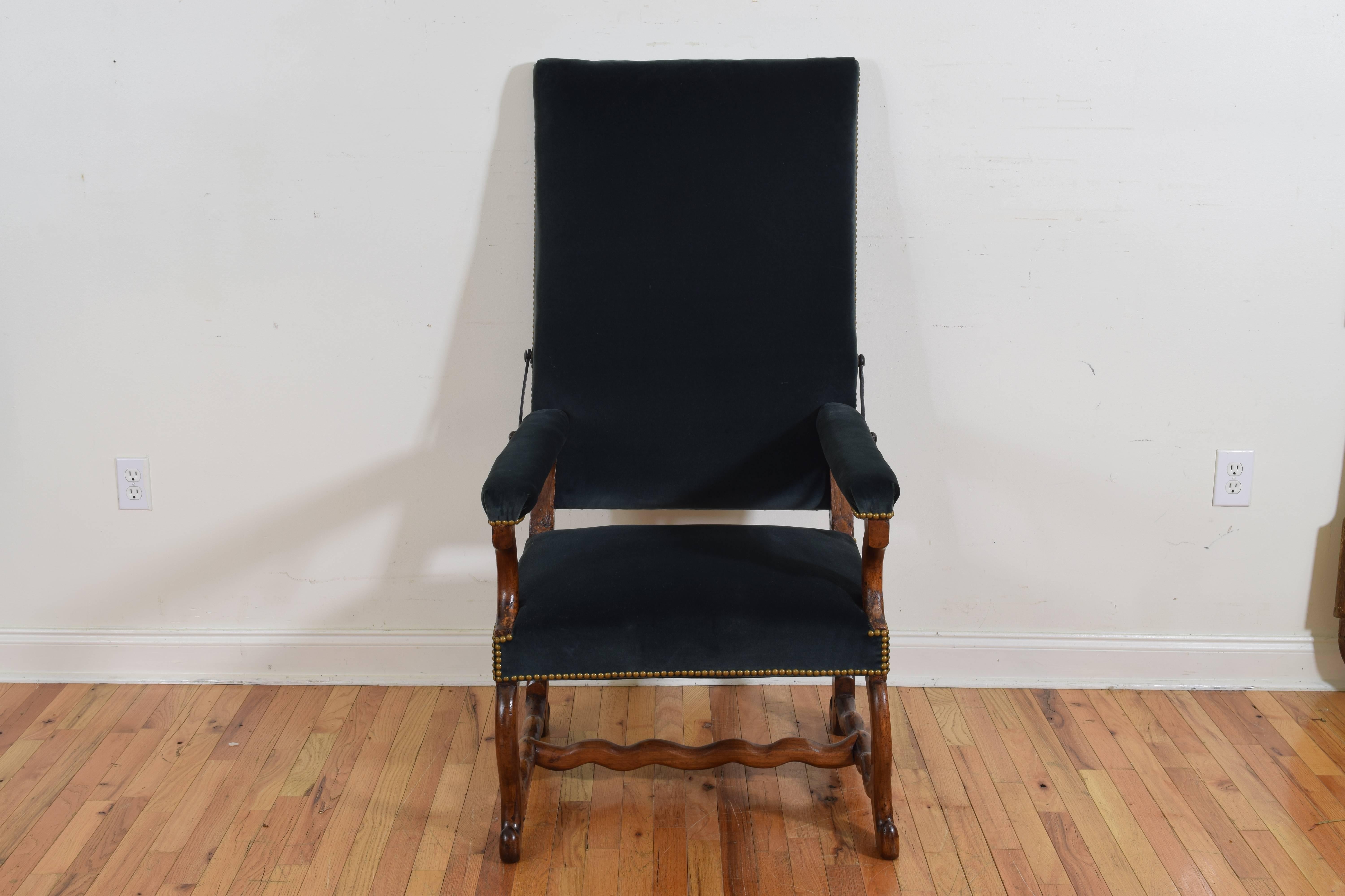 The large backrest, seat, and arms upholstered in velvet and trimmed in nailheads, the back is adjustable using an iron ratchet mechanism, having interesting legs and feet and joined by a shaped H-form stretcher.