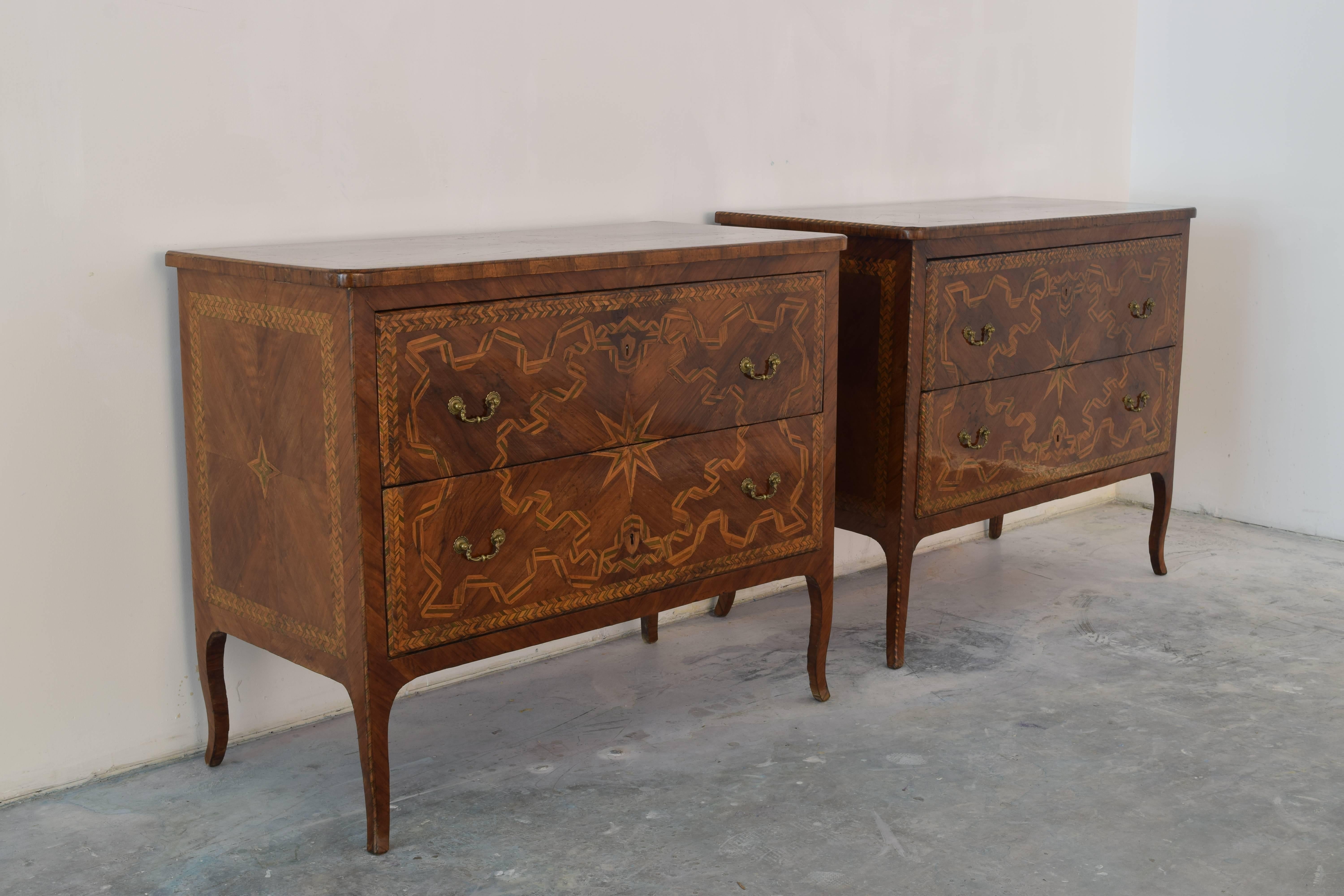 Constructed in the early third quarter of the 18th century in the Emilia Romagna region of Italy, specifically the town of Rolo, this exceptional and rare pair of commodes are completely veneered in walnut, tinted pearwood, and fruitwood veneer, the