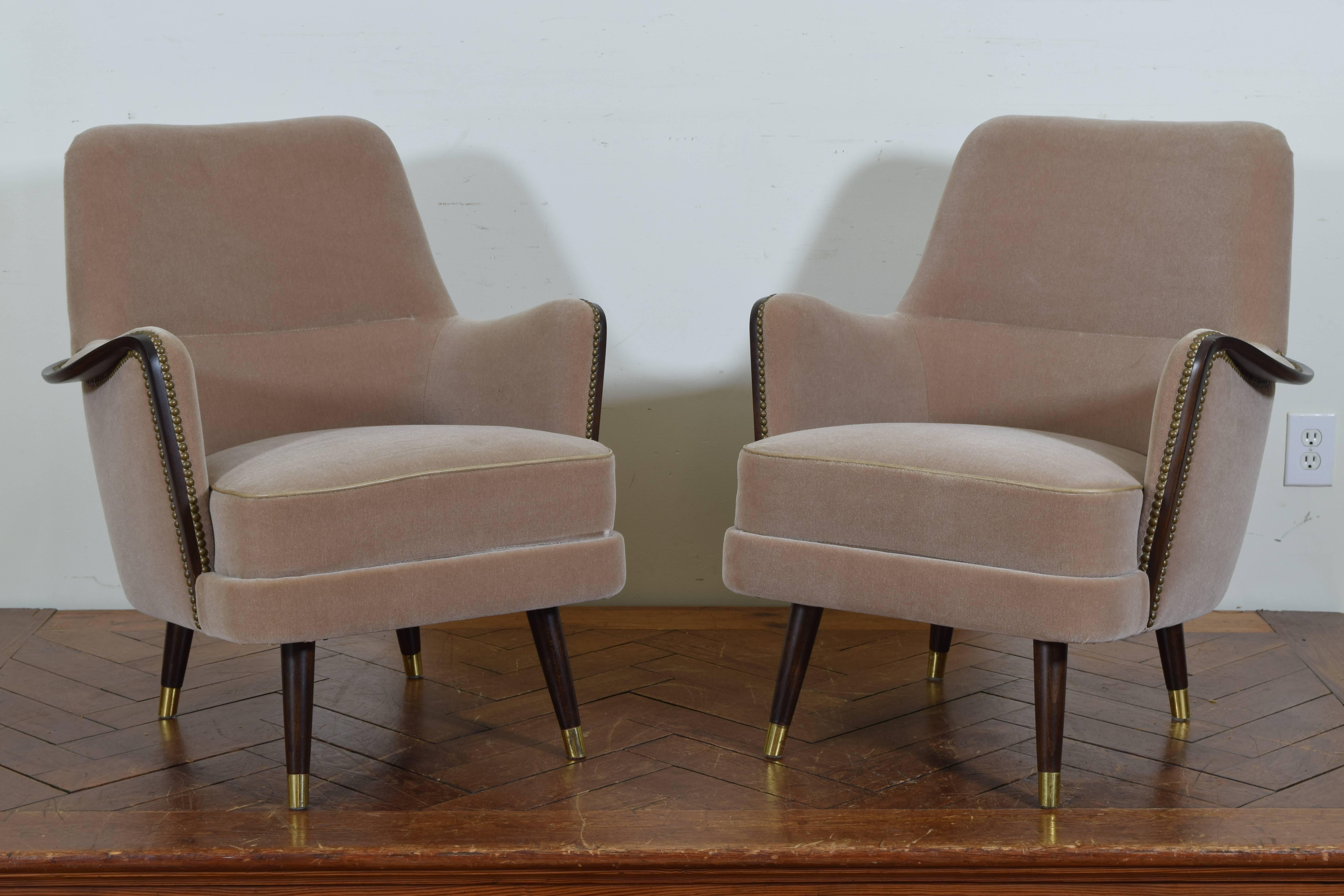 Having curved backs, the arms trimmed in mahogany, tapered legs with brass sabots.