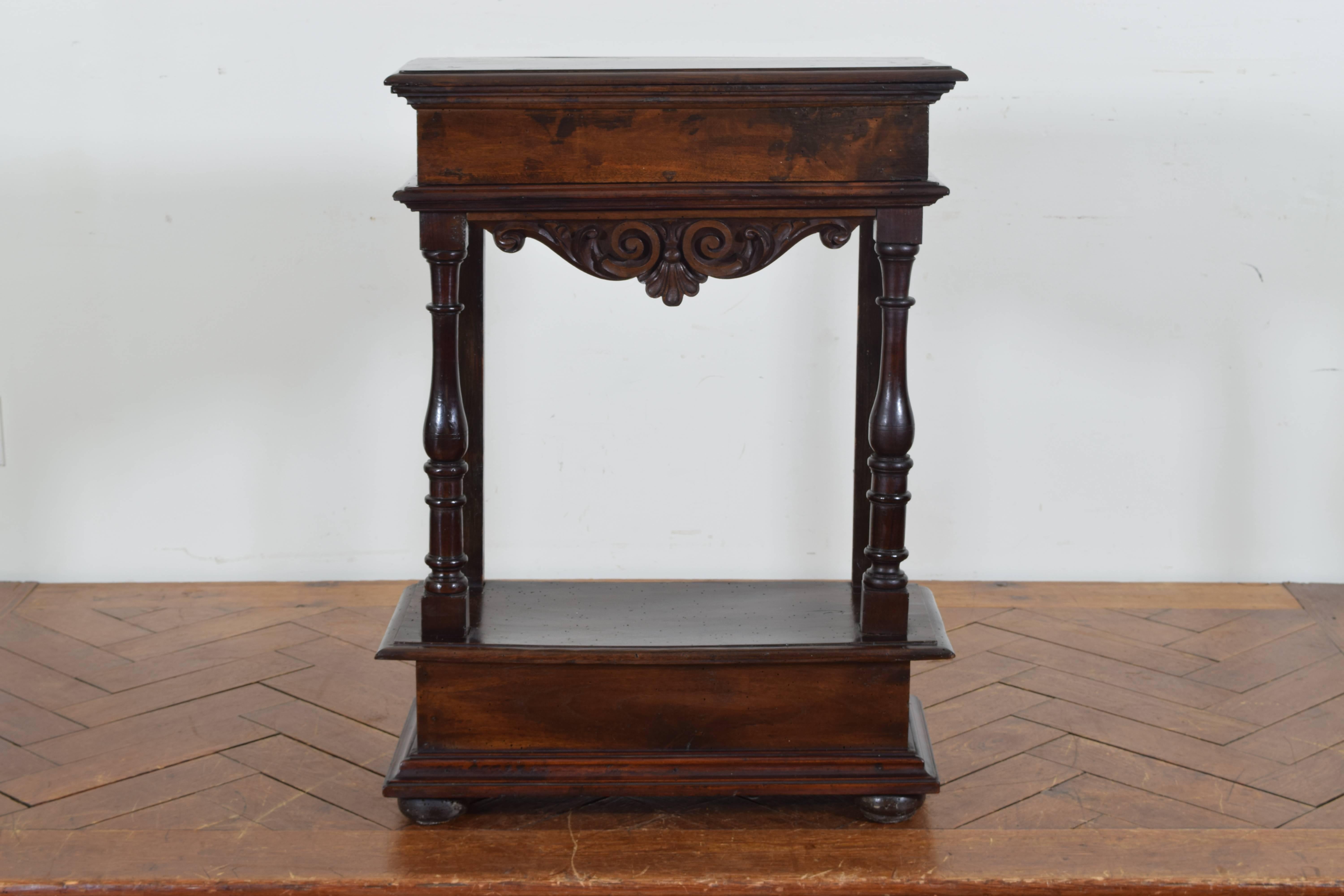 Having a rectangular top housing one-drawer with a decoratively carved apron, with turned front legs and flat rear legs, the lower cabinet with secret access from the rear, flattened bun feet.