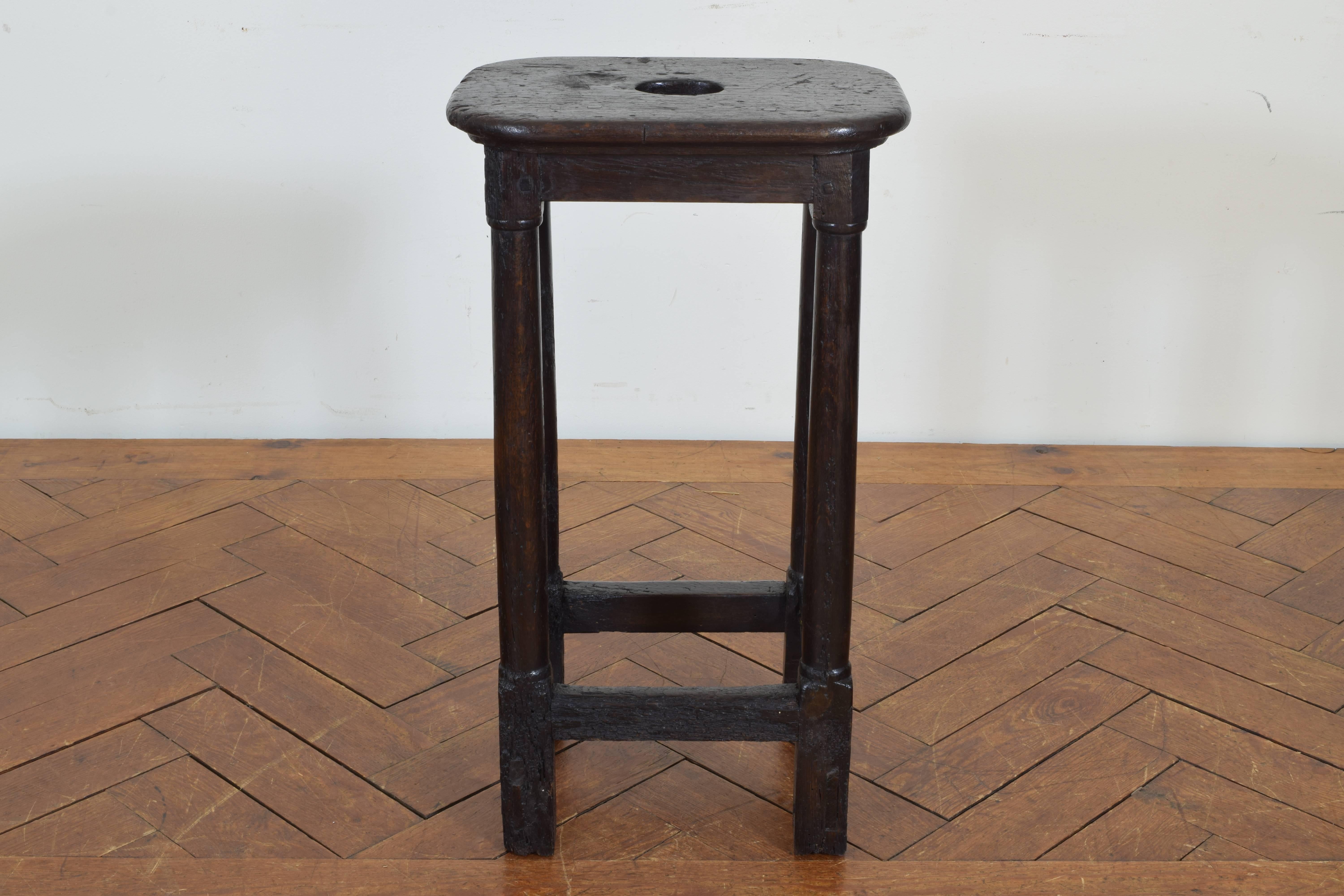 Made from oak with pegged construction. The legs are joined by a stretcher, the top having a carved hole used for handling.