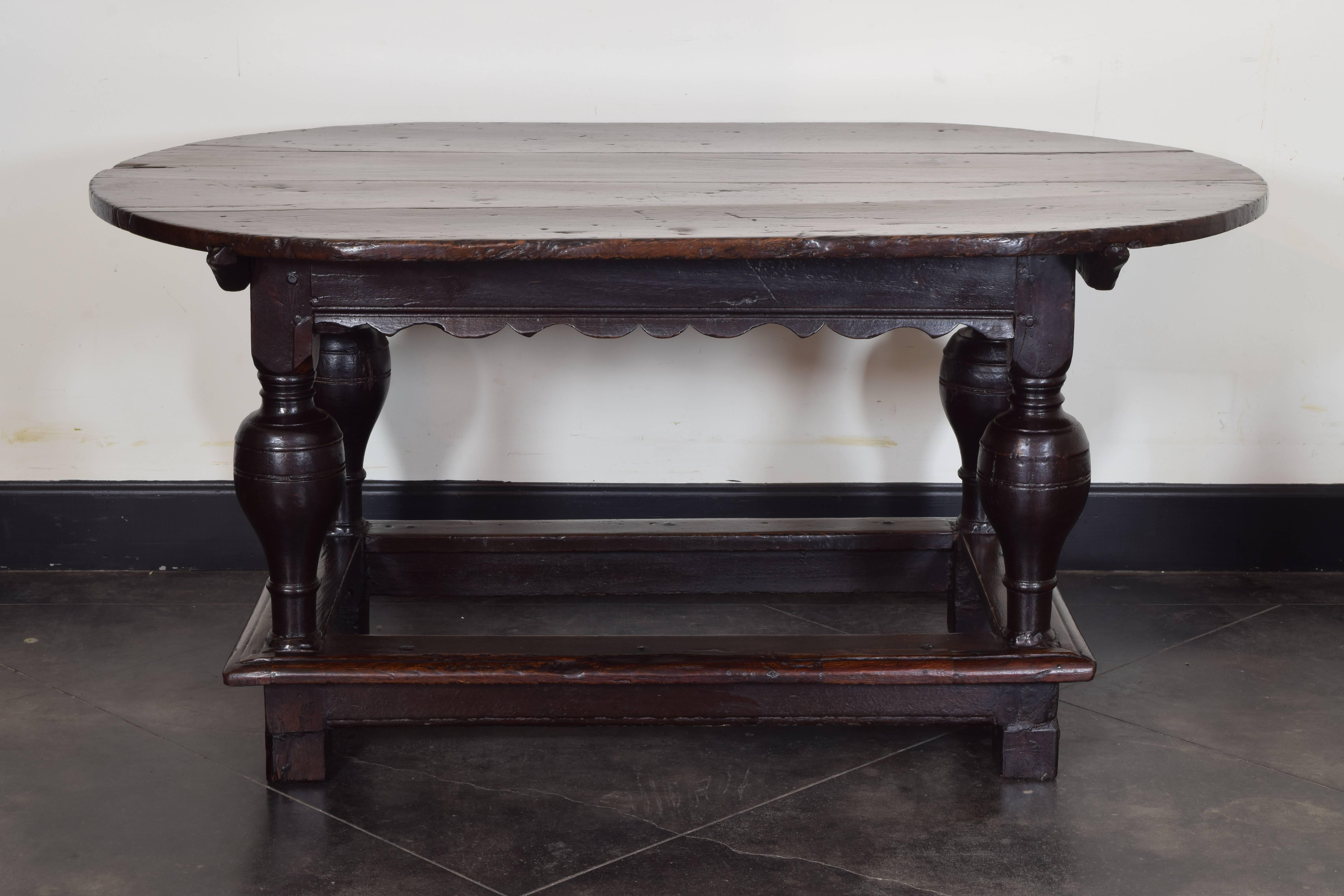 Having a four board oval top with a shaped apron, raised on baluster form columnar legs joined by a molded edge rectangular apron, the legs continuing to square block feet.