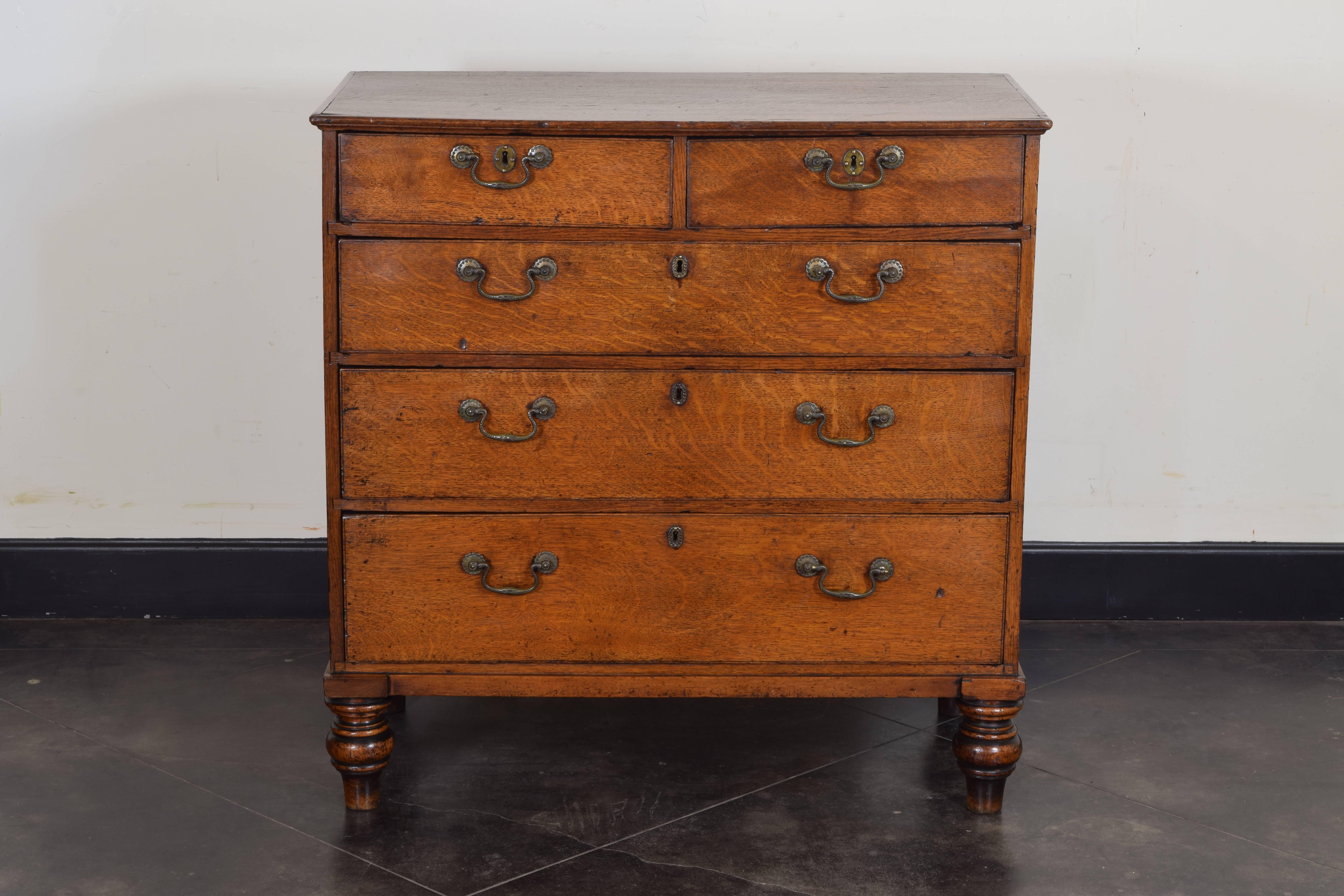Having a molded edge oak rectangular top above an oak case housing two smaller drawers and three larger drawers, retaining original hardware, raised on nicely turned walnut feet.