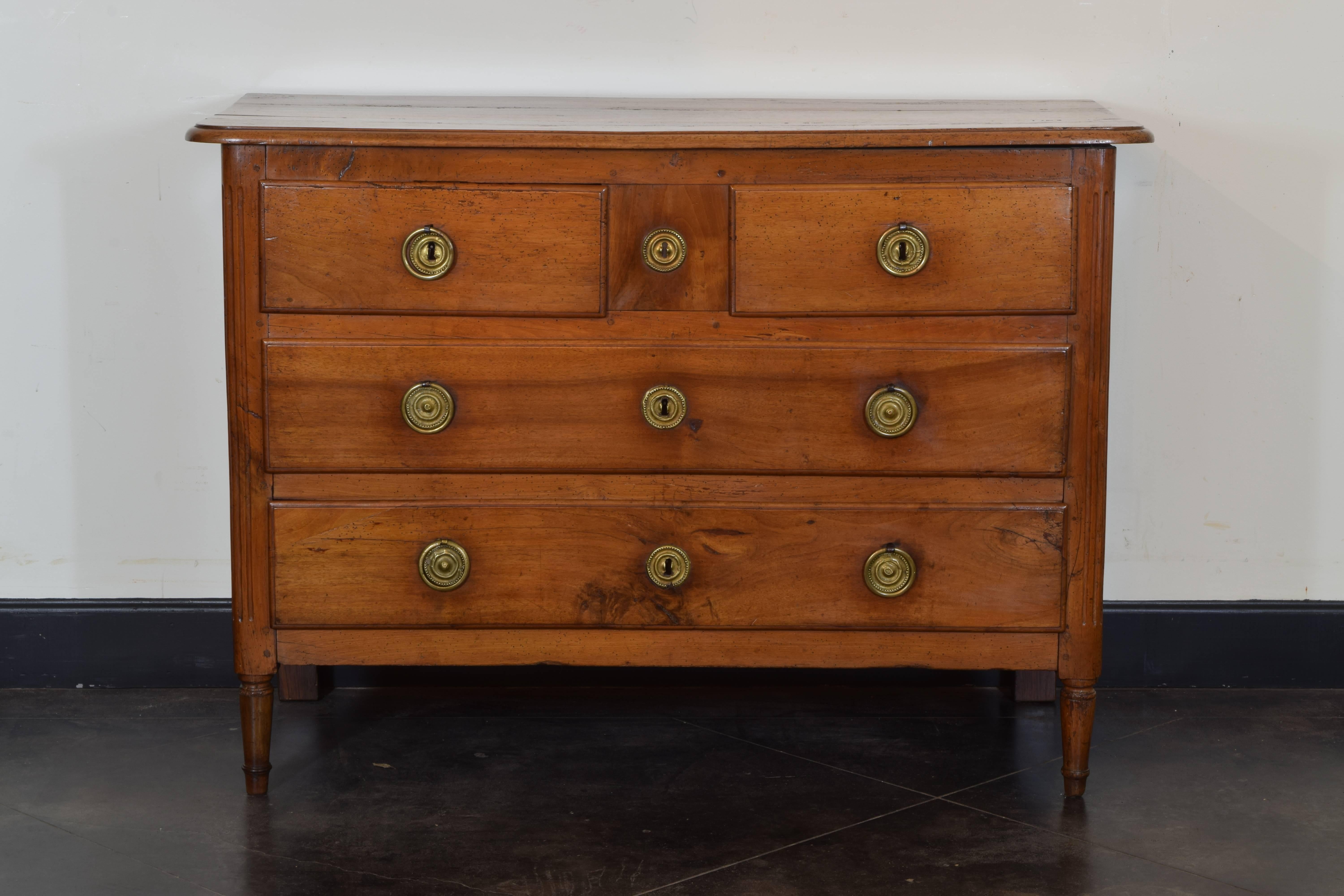 Having a rectangular top with rounded front corners and a molded edge, the case housing two small drawers over two larger drawers and retaining original brass pulls and locks, the front with fluted corner detail and raised on round tapering front