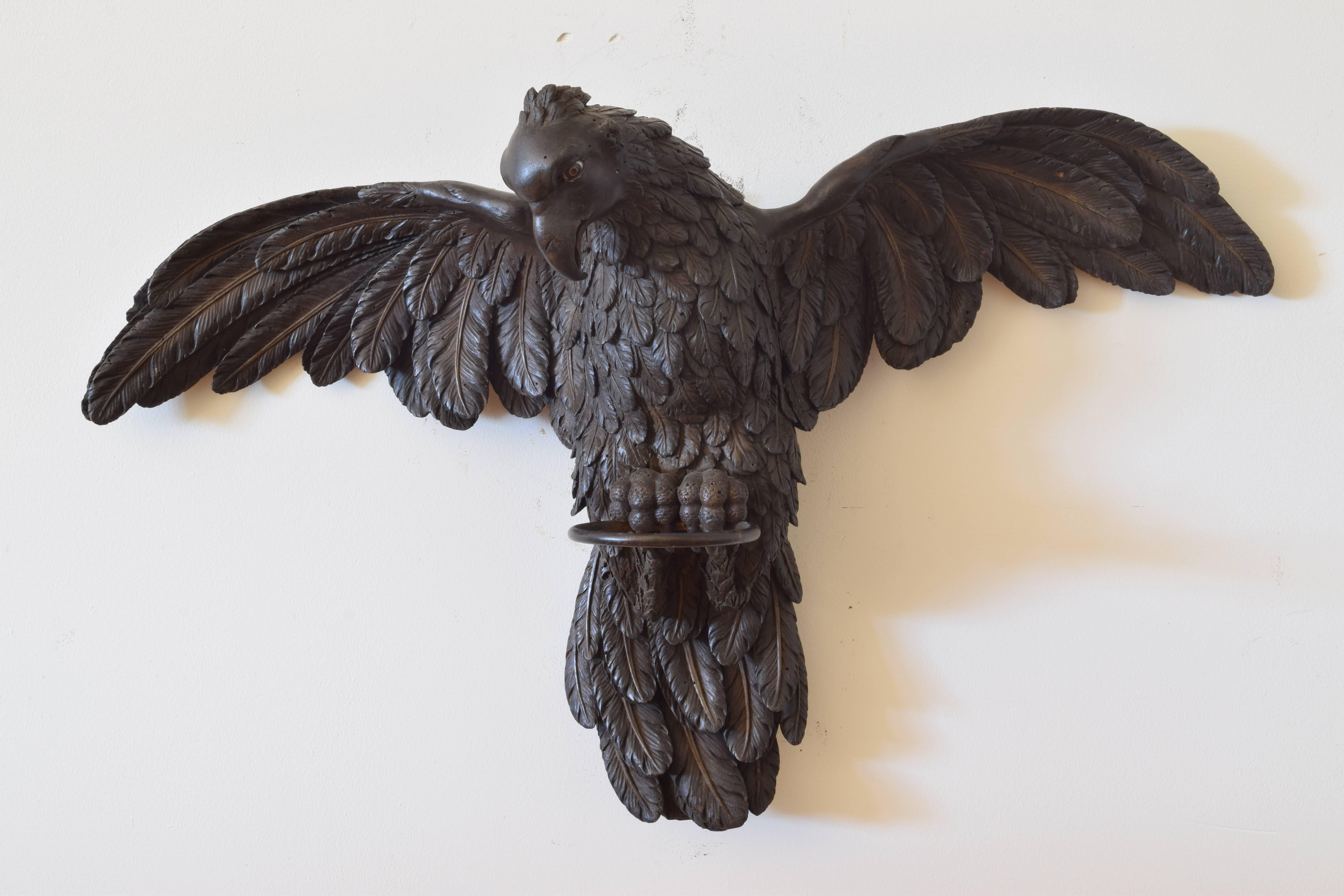 In excellent condition, beautifully carved with detailed feathers and talons, the eyes painted, retaining iron ring which was likely used for a fabric enclosure atop a poster bed.