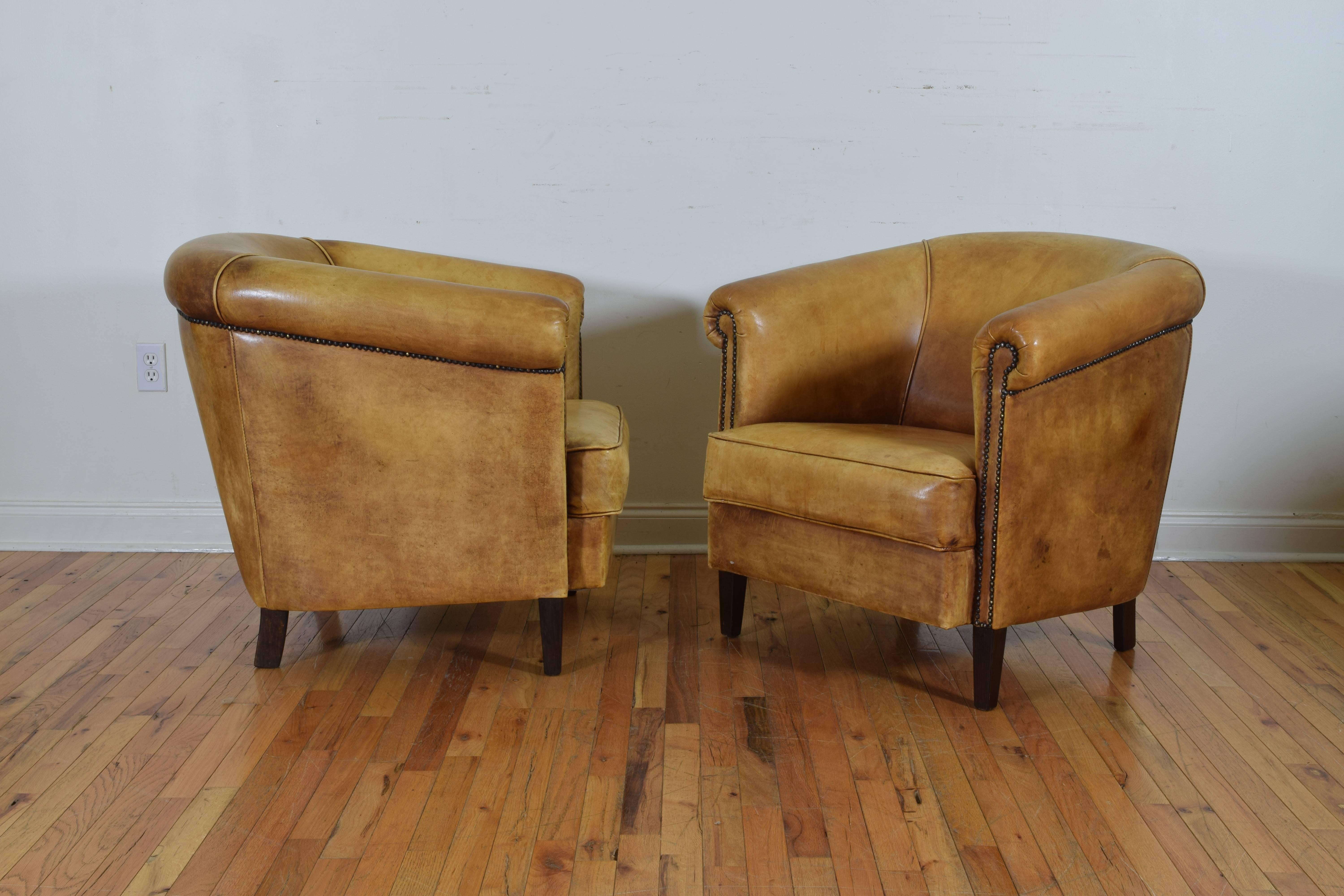 Having rounded backs and tight cushions, trimmed in nailheads, raised on square tapering legs.