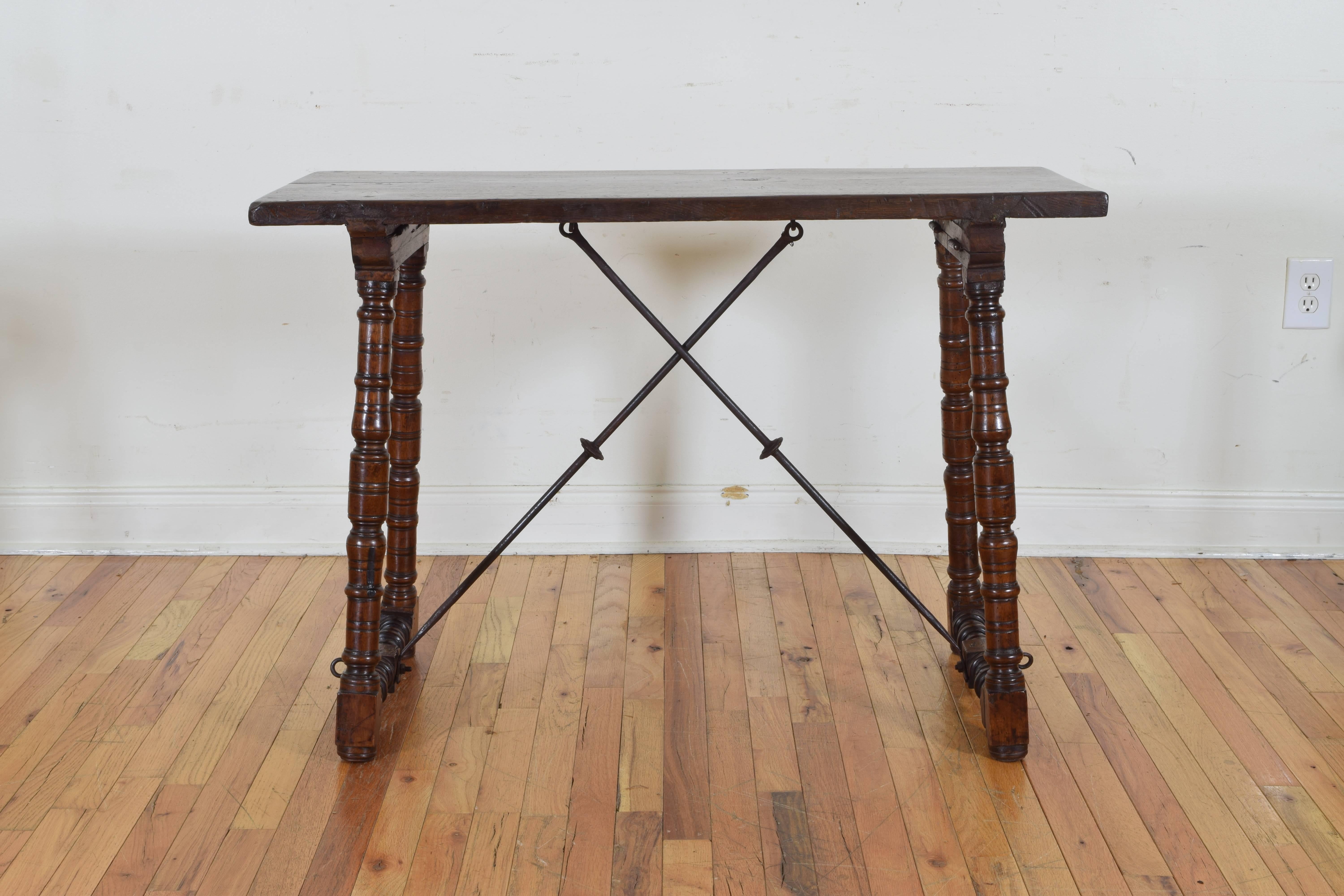 The rectangular top raised on turned trestle-form legs joined by a wrought iron X-form stretchers.
