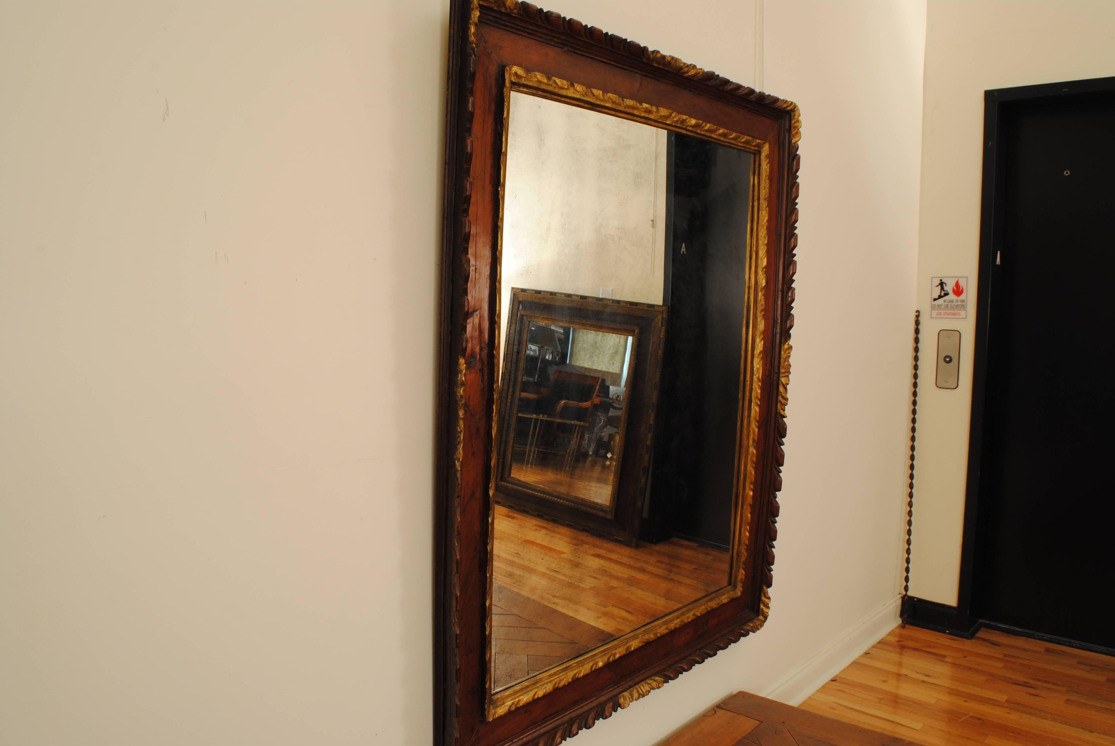 Italian, Piemonte, carved and veneered walnut and giltwood frame/mirror, early 18th century of large scale and having a rear step-molded edge with a flared carved molding, the corners and center sections gilded, the flat inner surface is veneered,