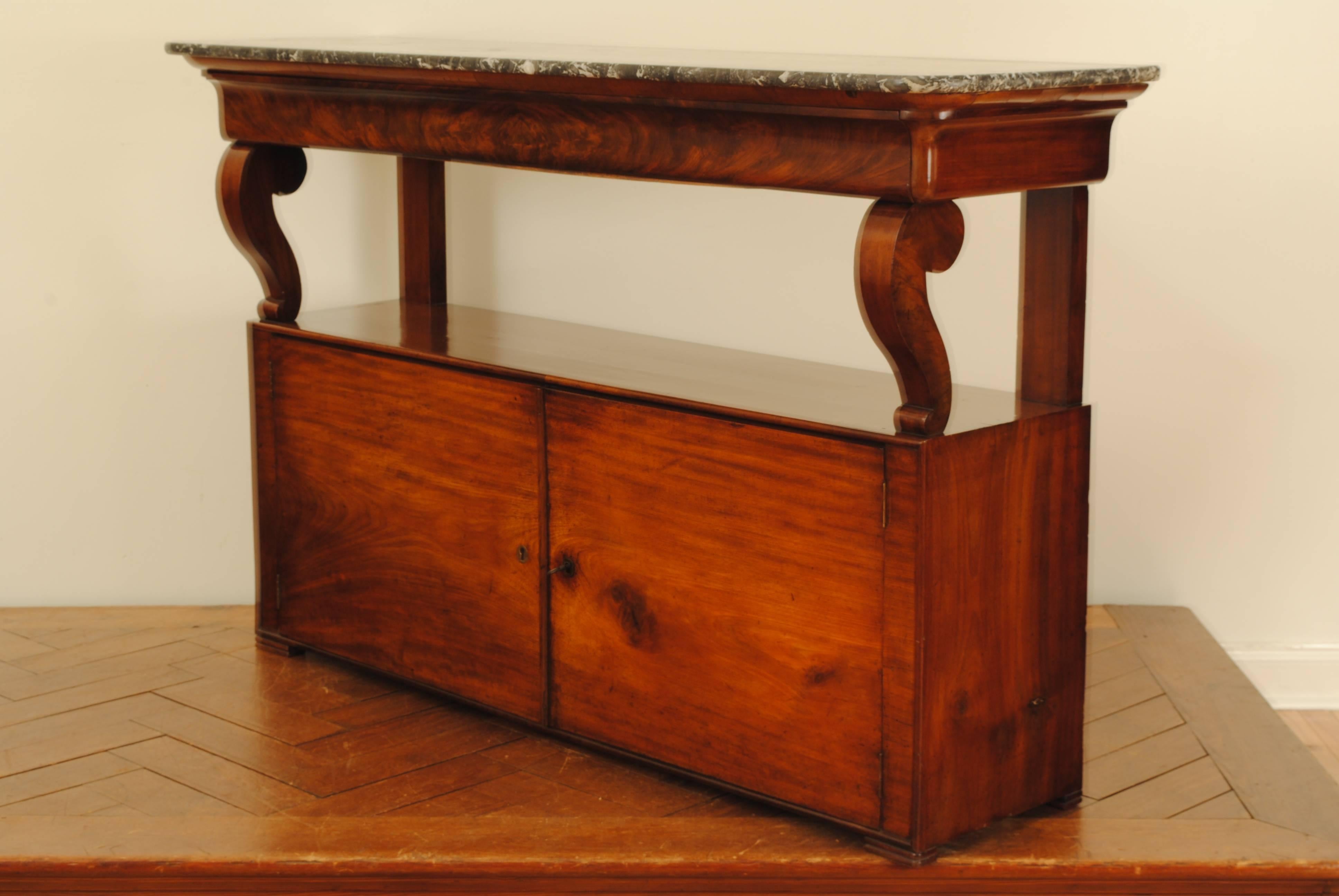 Having a grey and white veined marble top with rounded front corners atop a conforming case with front curved supports above an upper shelf, the lower portion with two locking doors revealing four storage compartments, raised on small flattened