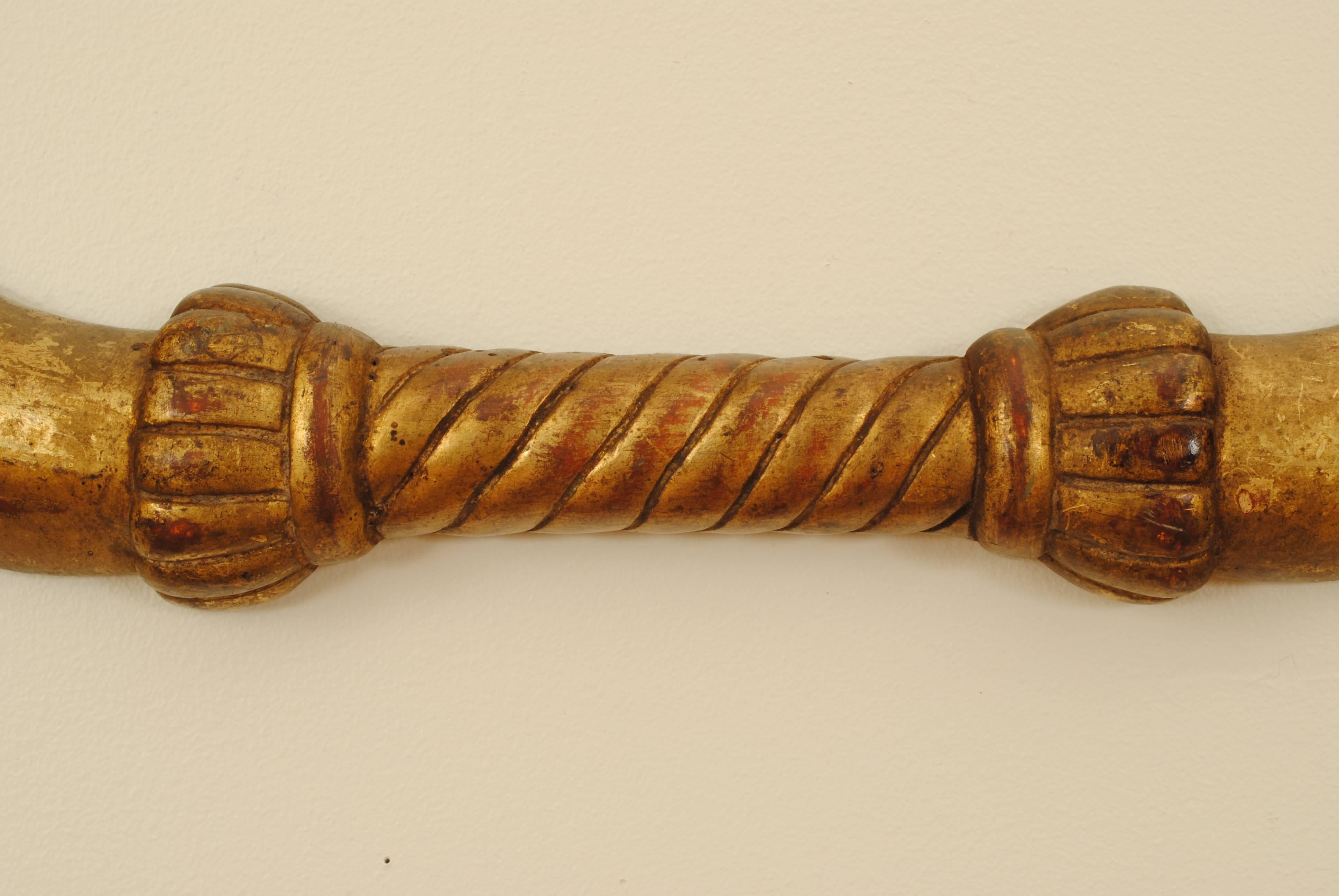 in the shape of a bow with a detailed center grip and swans heads on the ends, the reverse side flat and meant to hang on a wall