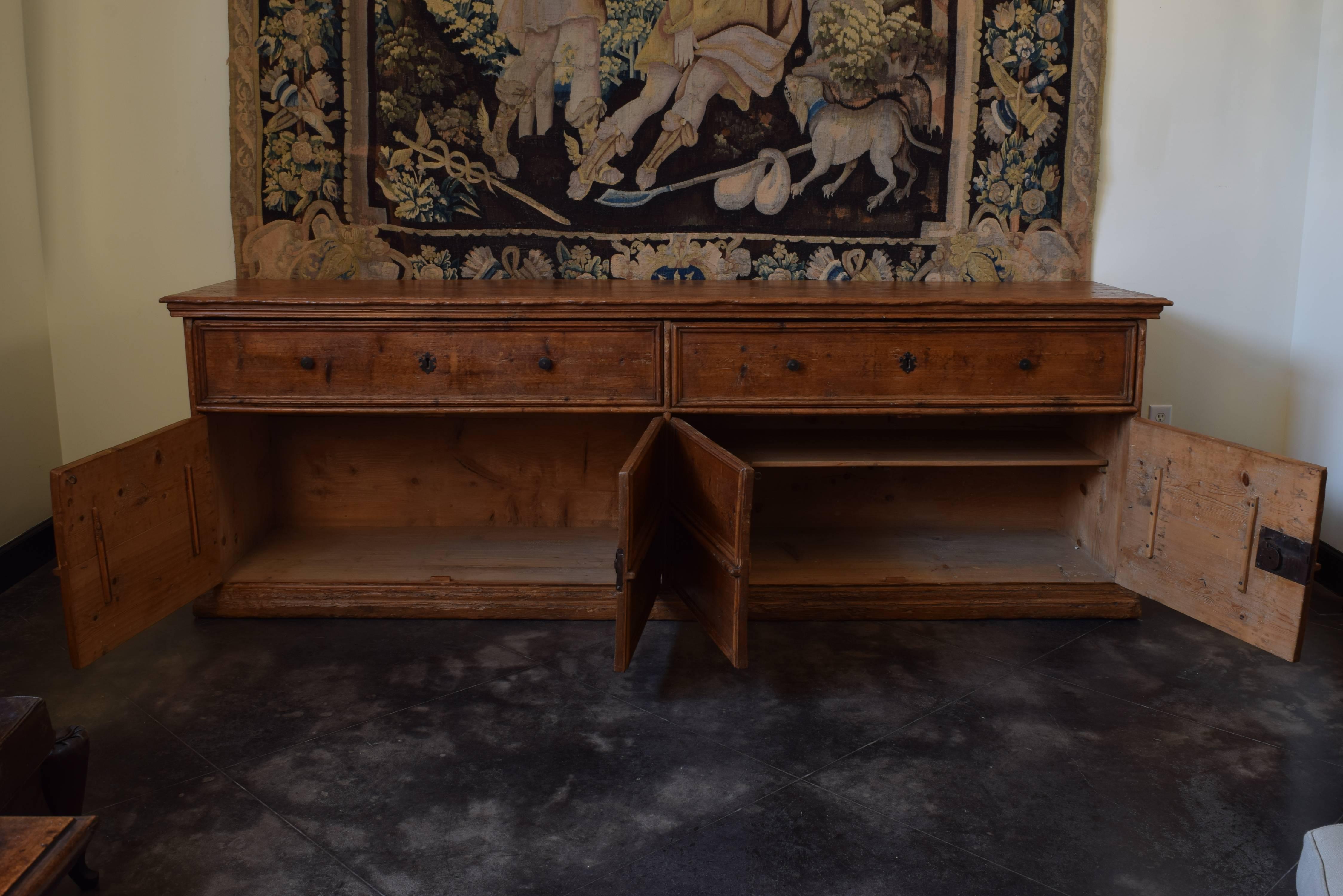 The rectangular top with a molded edge above a conforming case housing two large drawers over four doors, the interior with shelving and retaining antique iron locks, the case resting on a molded plinth base. This cabinet was used to hold the