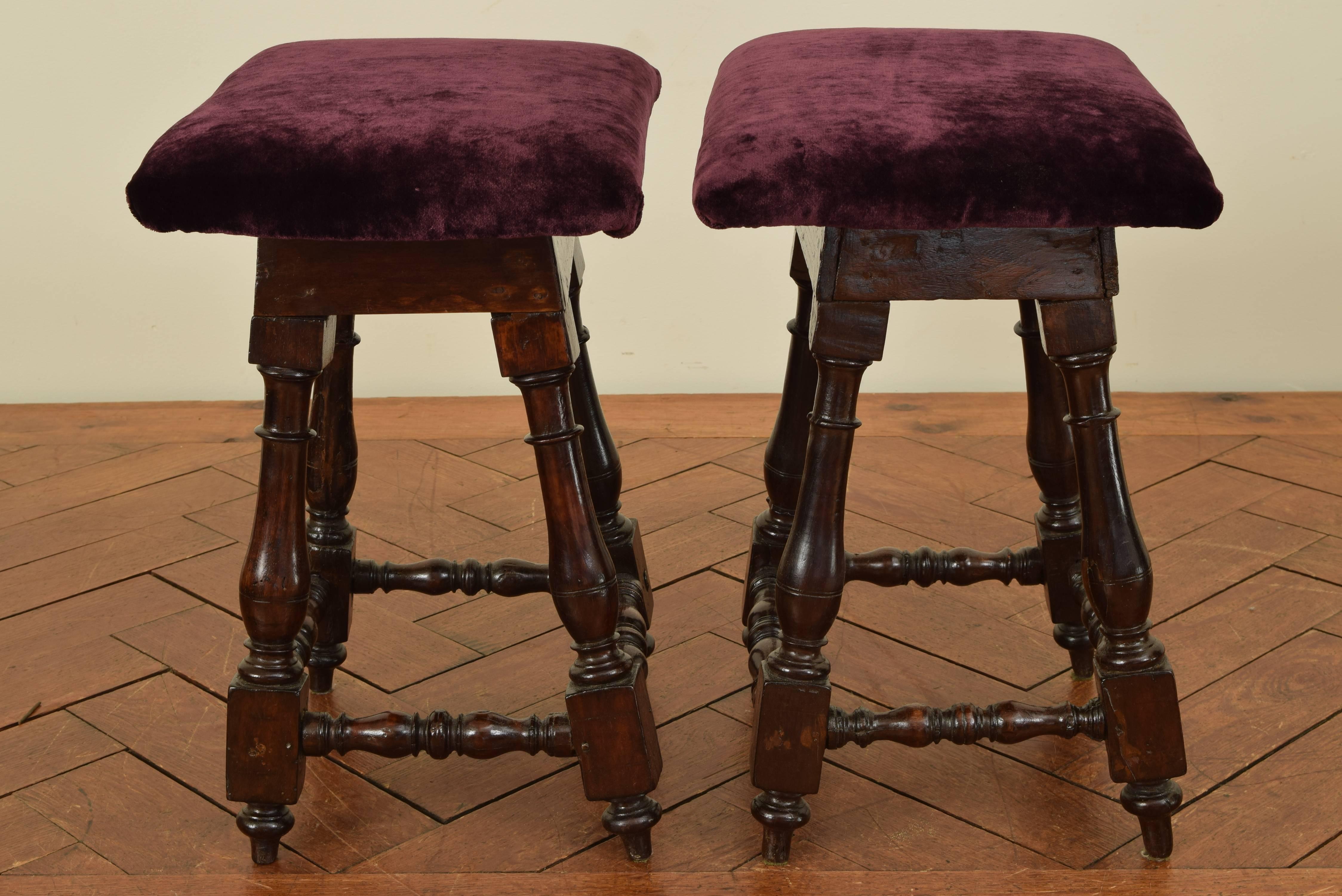 The rectangular tops upholstered in purple velvet and raised on slanted turned legs connected by turned stretchers, tapered feet.