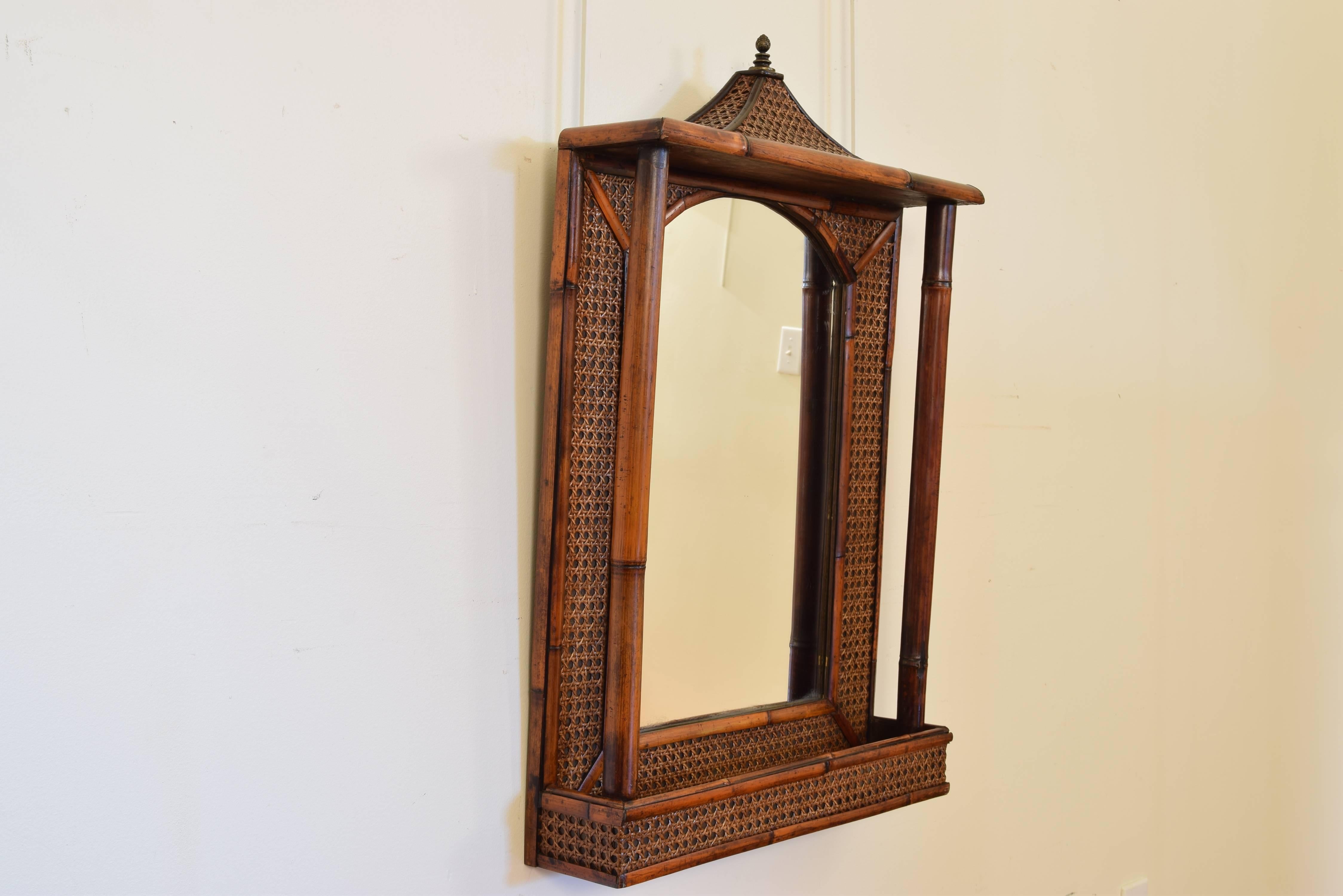 Having a pagoda shaped top with a brass finial, the mirror between bamboo columns, the lower section a tray.