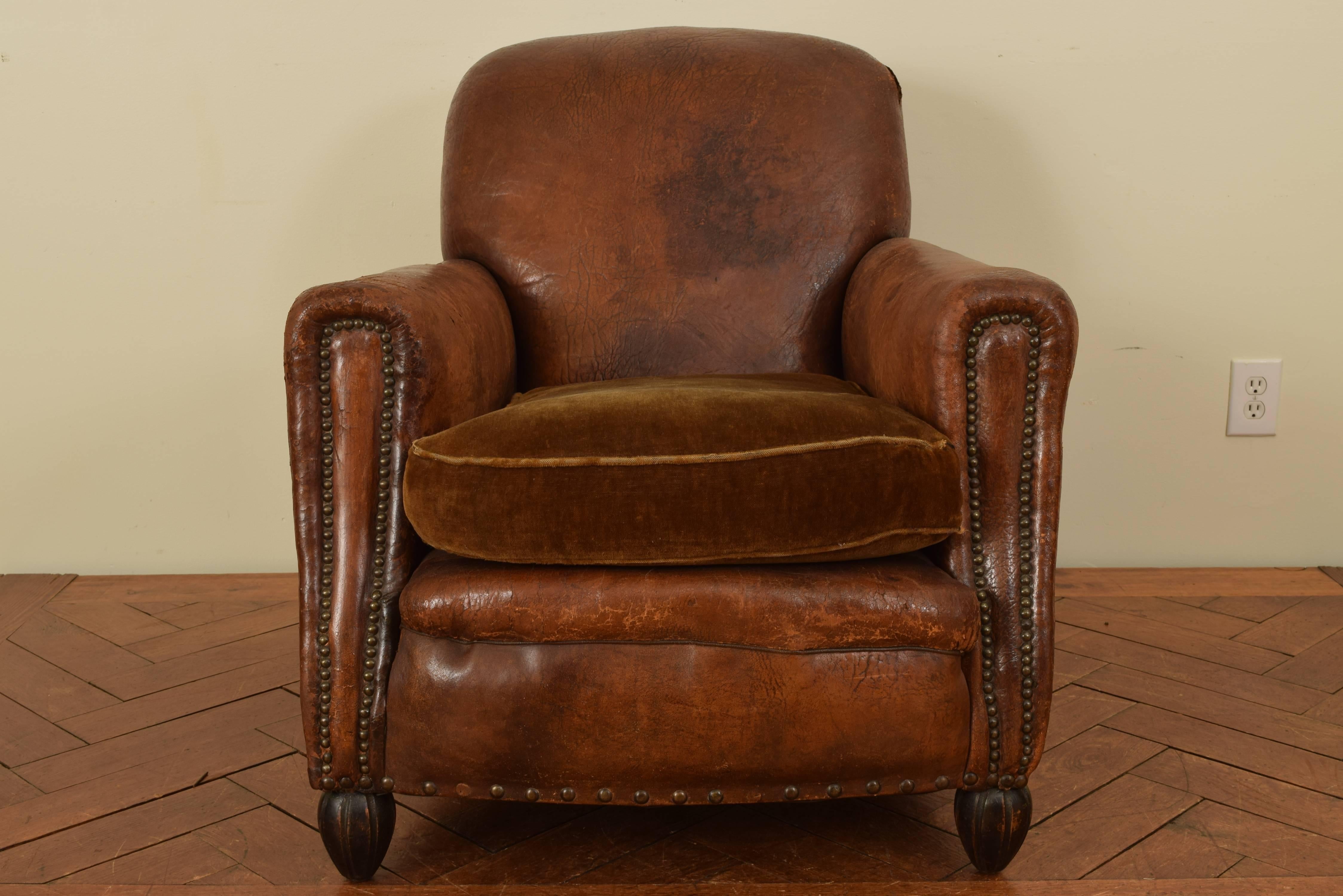 Very comfortable and having a nice lean, the leather upholstery trimmed in patinated brass nailheads, having a down filled velvet cushion, raised on shaped front feet and rear sloping feet.