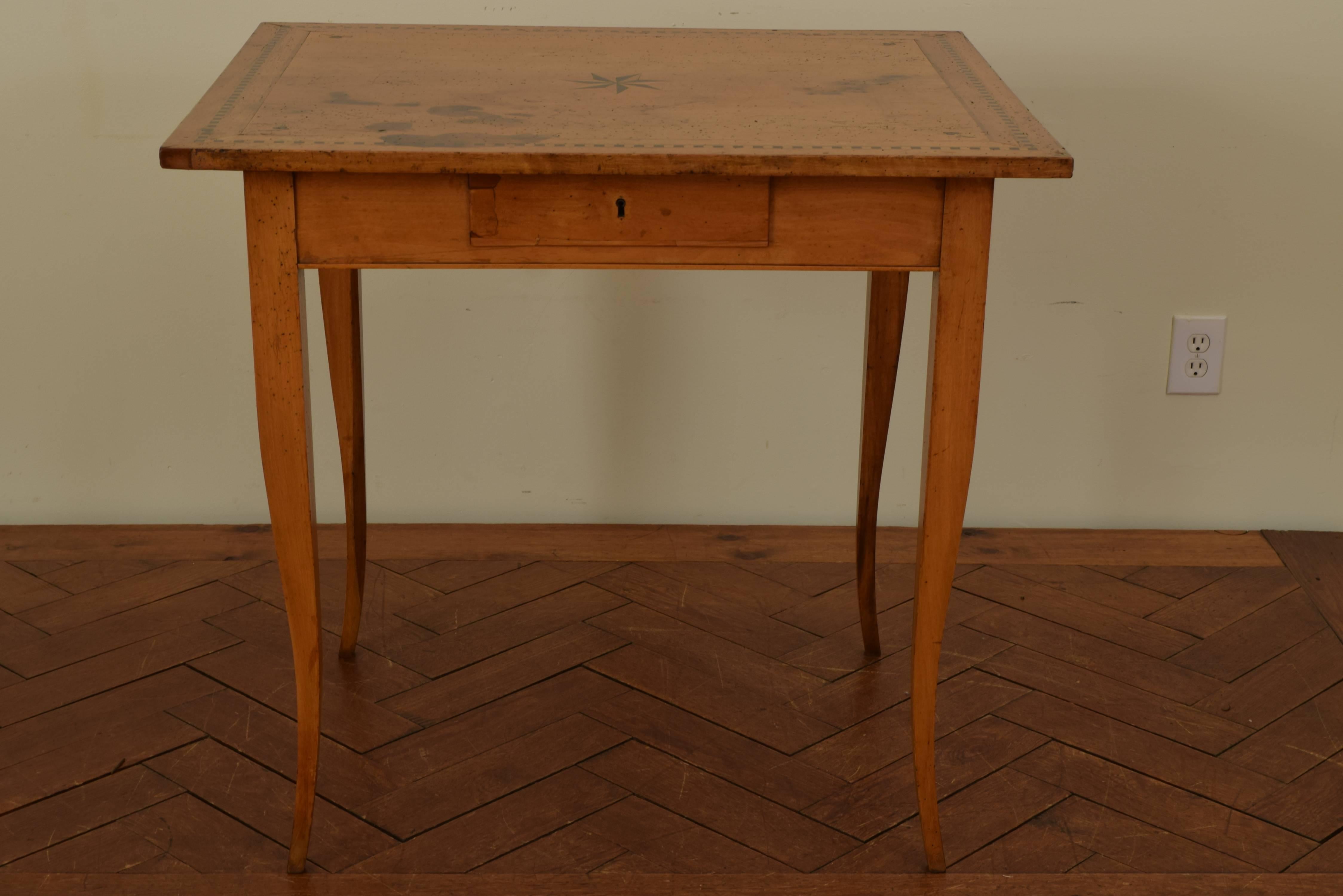 Neoclassical one-drawer table. The rectangular top with an ebonized block border, clover leaves in the corners and a centered star medallion, the apron housing one locking drawer, raised on slightly cabriole legs.