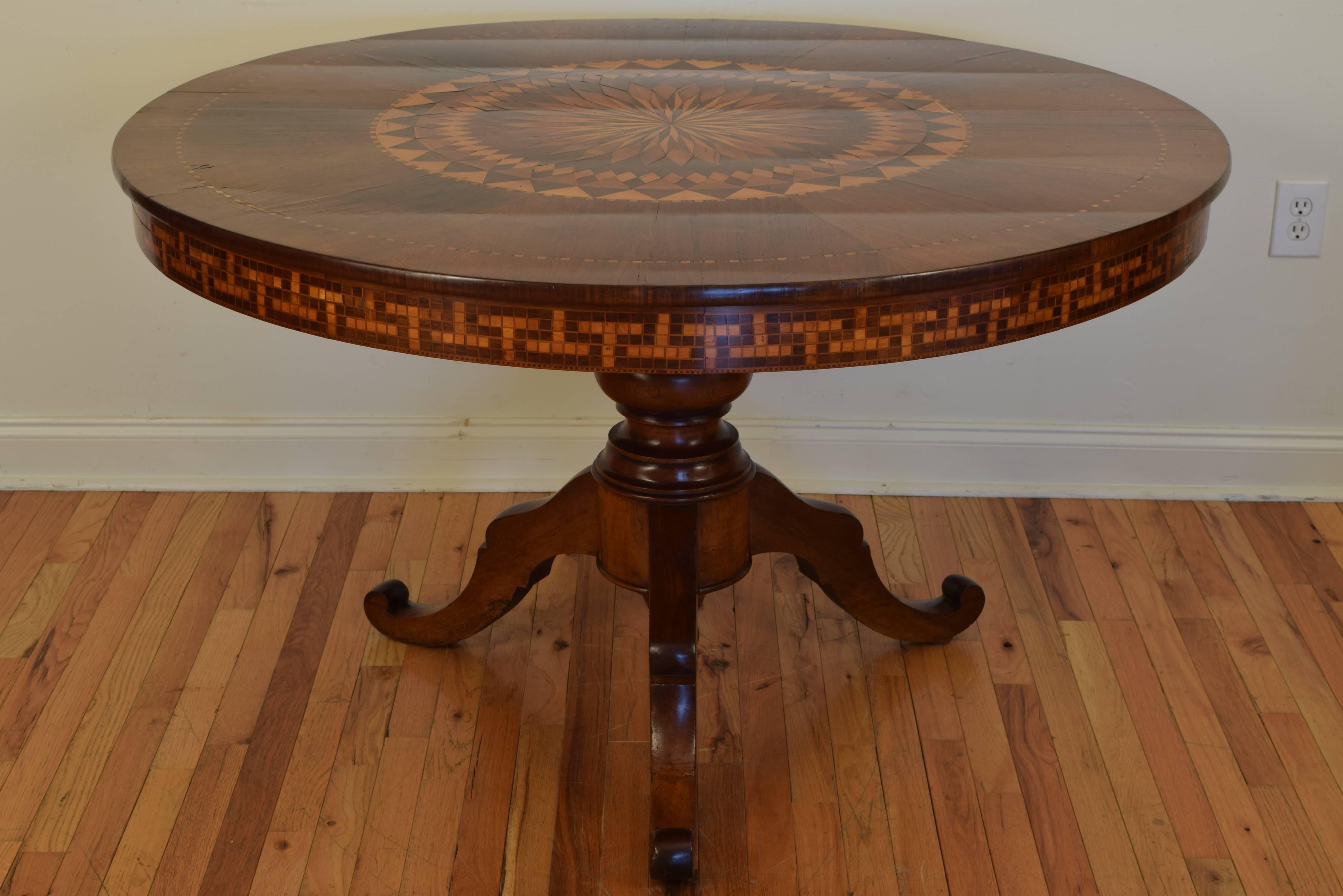 The circular top having a beautifully inlaid large center medallion with an outer gap-banded detail, the apron very unique in its geometric pattern raised on a turned columnar support with a tripartite base and shaped feet, 2nd Quarter of 19th