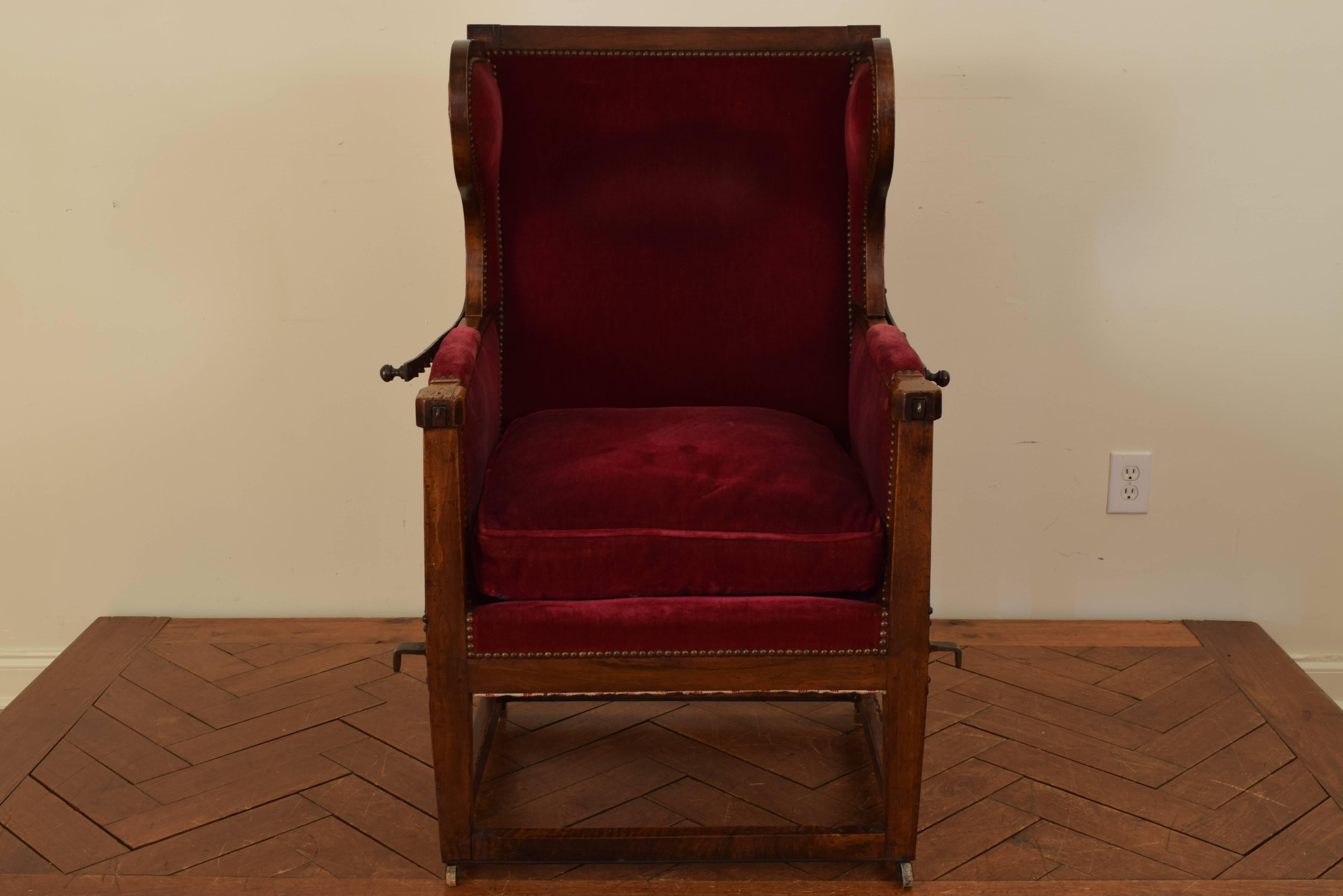 The straight back with shaped wings and hinged to recline, attached to the lower chair with adjustable steel supports, having a down filled seat and raised on slightly tapering legs joined by a box stretcher, raised on small wheeled casters.